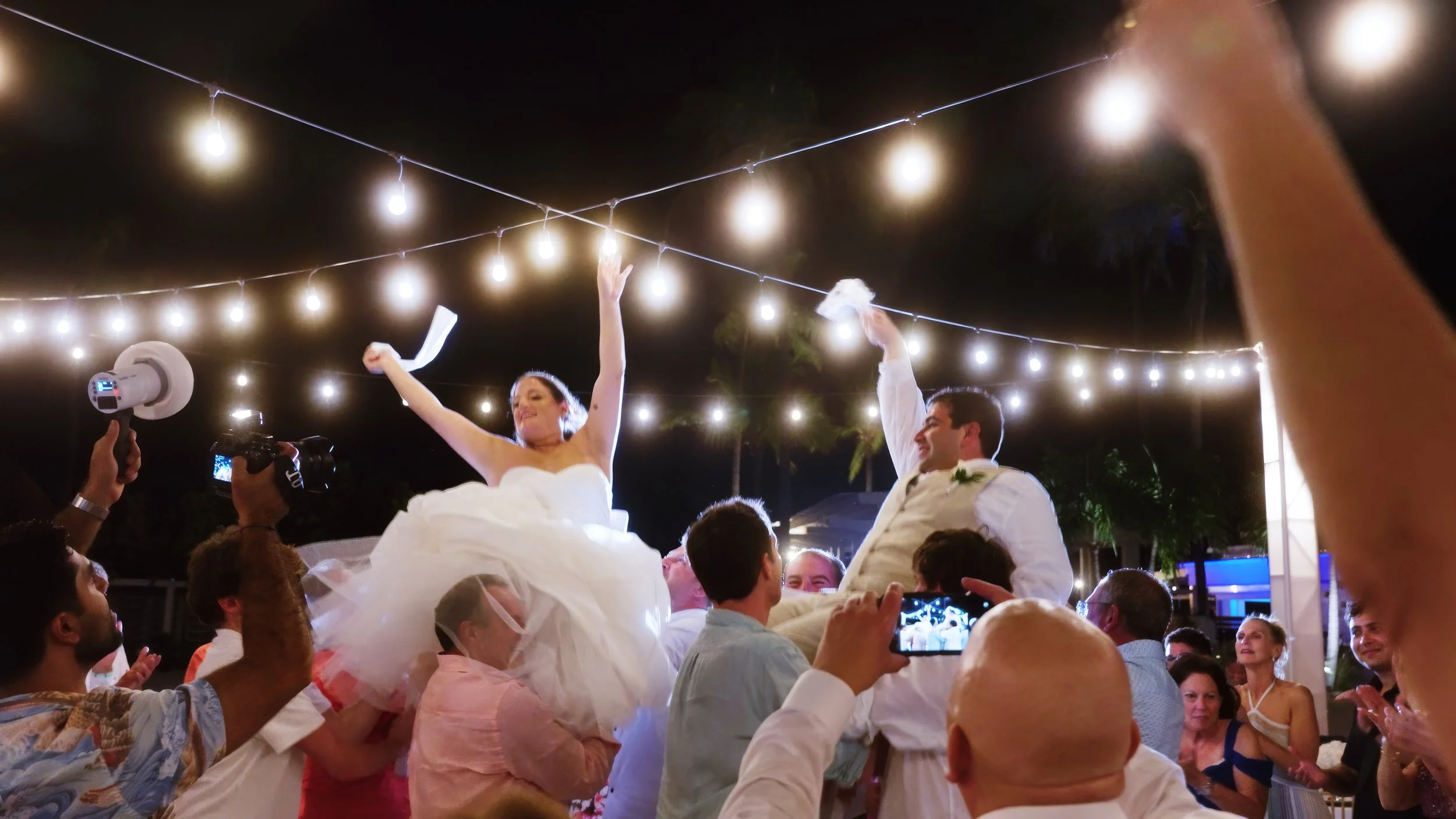 Newlyweds lifted on chairs during the hora at Aruba Marriott Resort & Stellaris Casino