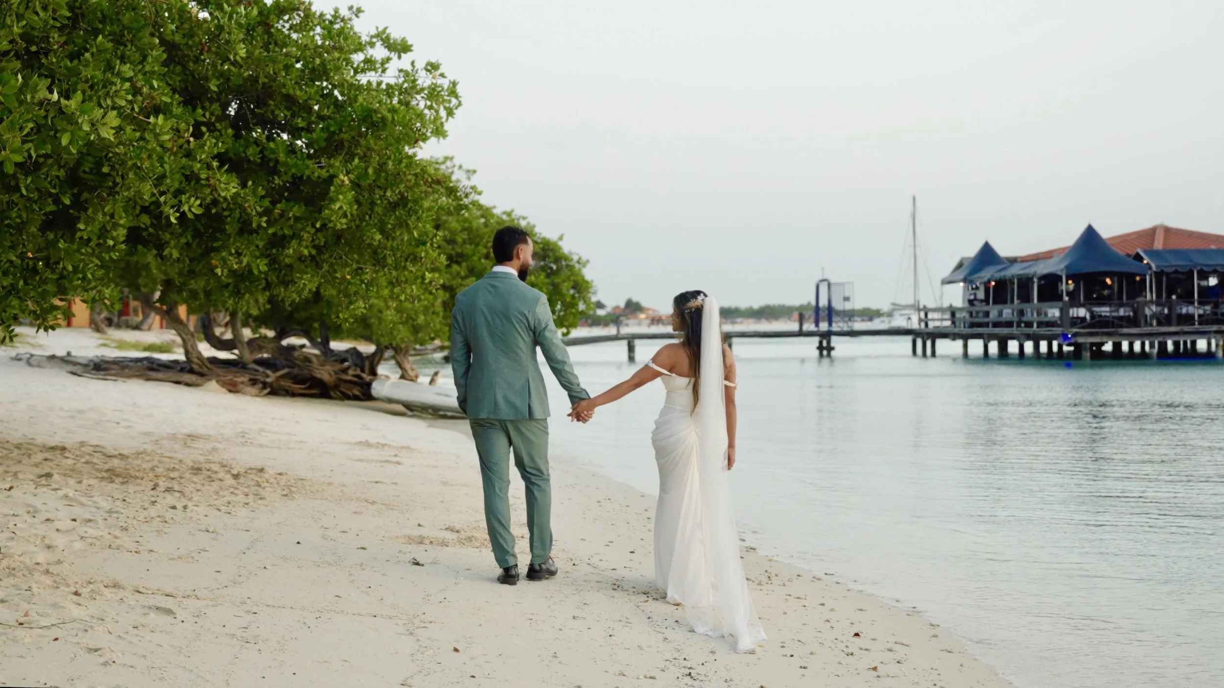 Bride and groom walk hand in hand along Surfside Beach, Aruba after their wedding ceremony