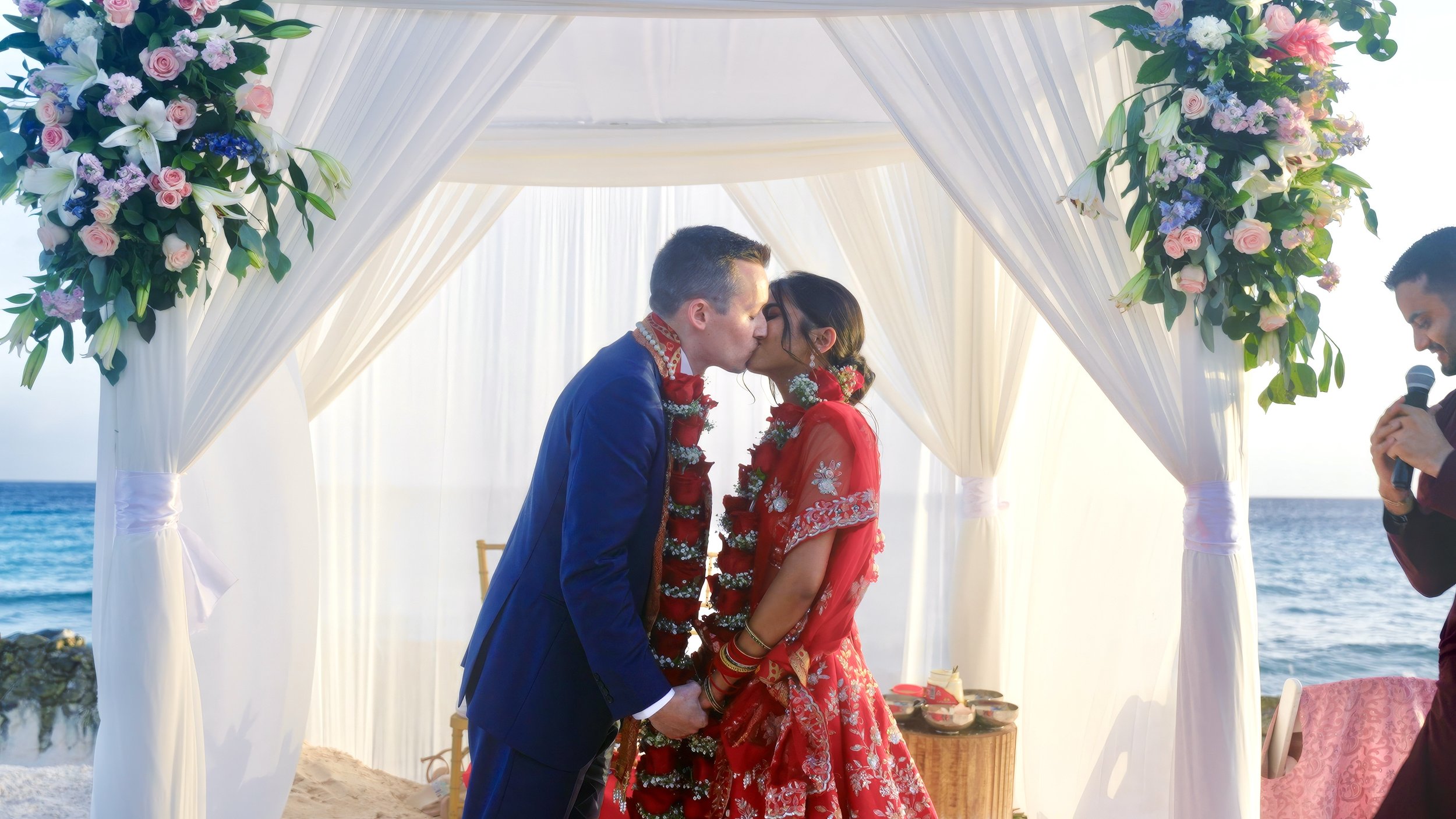 Aruba wedding couple's first kiss under a floral canopy at their Hindu ceremony on Renaissance Private Flamingo Island, Aruba