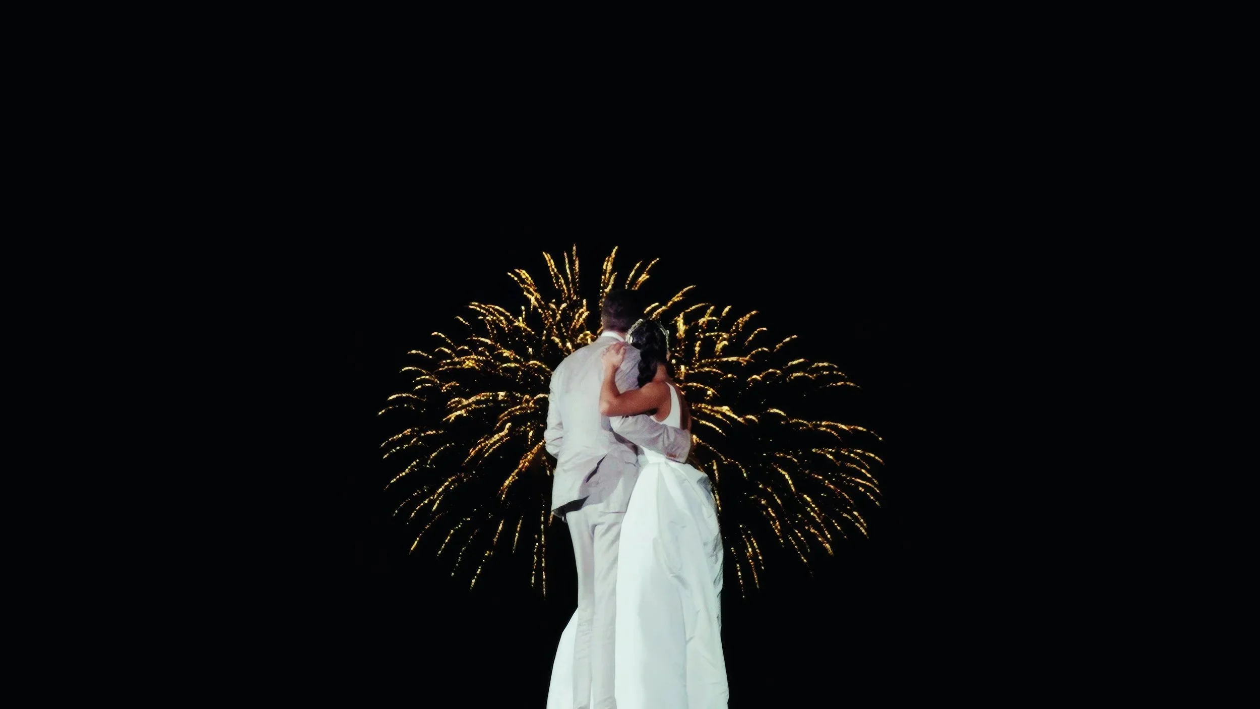 Aruba newlyweds embracing under fireworks at their Tierra del Sol Aruba wedding reception