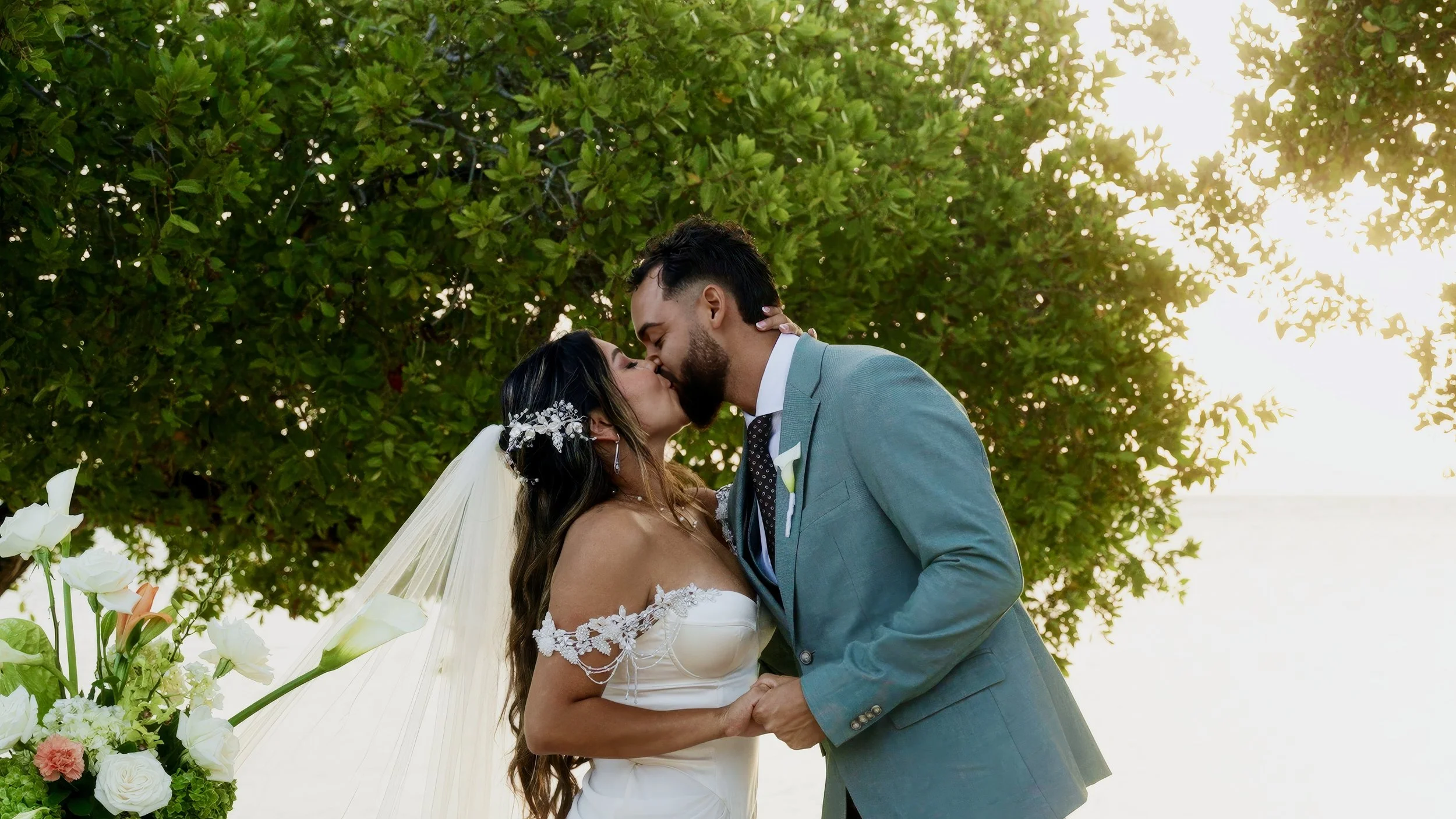 Aruba bride and groom kissing under the trees at Surfside Beach in Oranjestad, Aruba, filmed by Aruba wedding videographer Wedding Films by Mira