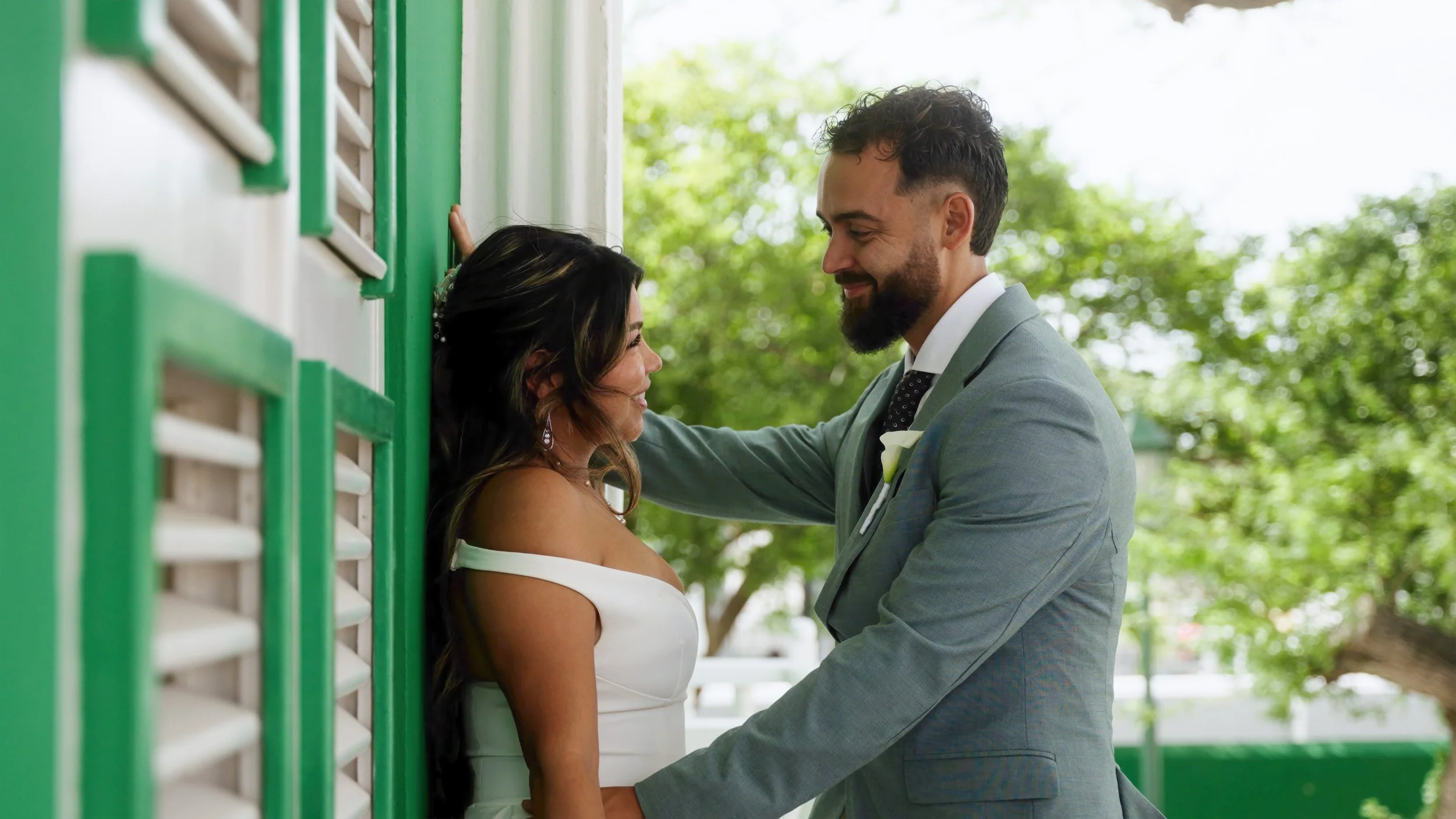Bride and groom embrace in front of green shutters in downtown Oranjestad, Aruba after their courthouse wedding