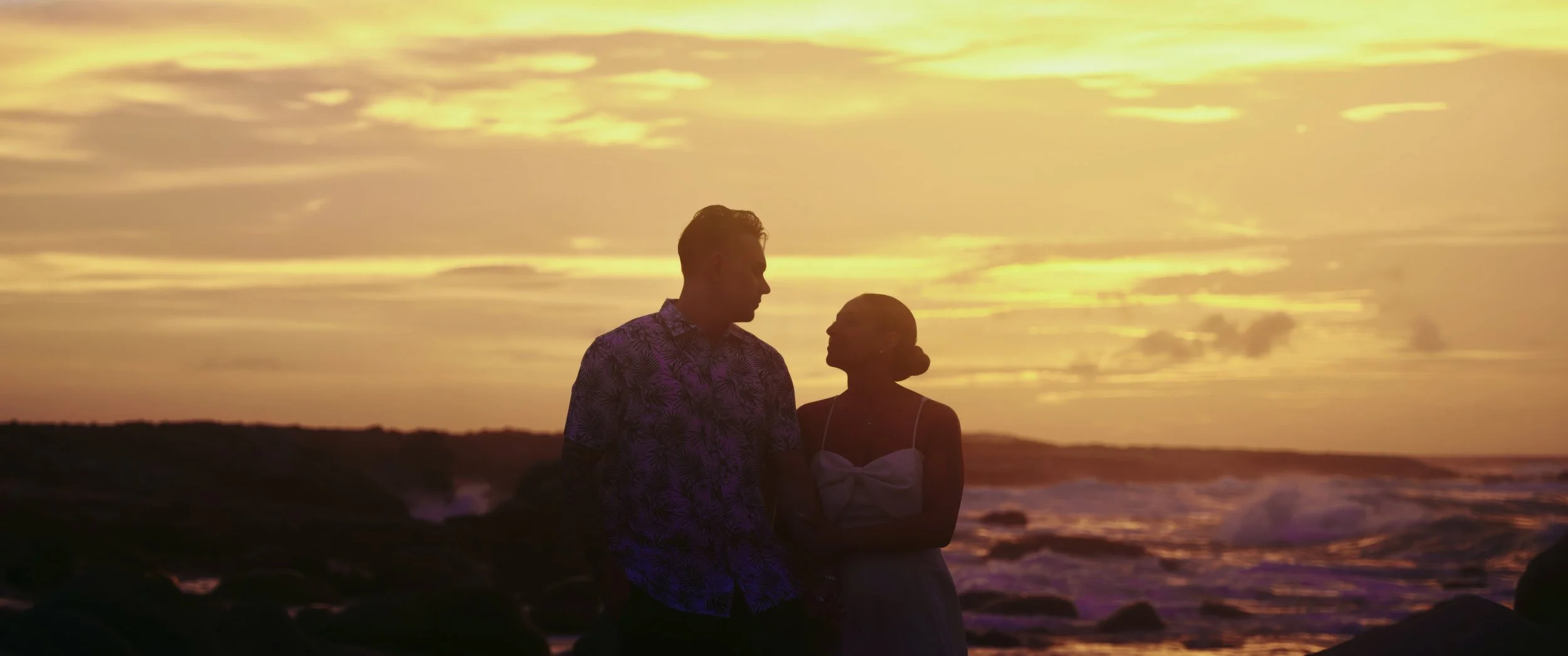 Aruba wedding couple Gianna and Daniel embracing at sunset, silhouetted against the sky at their Holiday Inn Resort Aruba beach wedding in Palm Beach