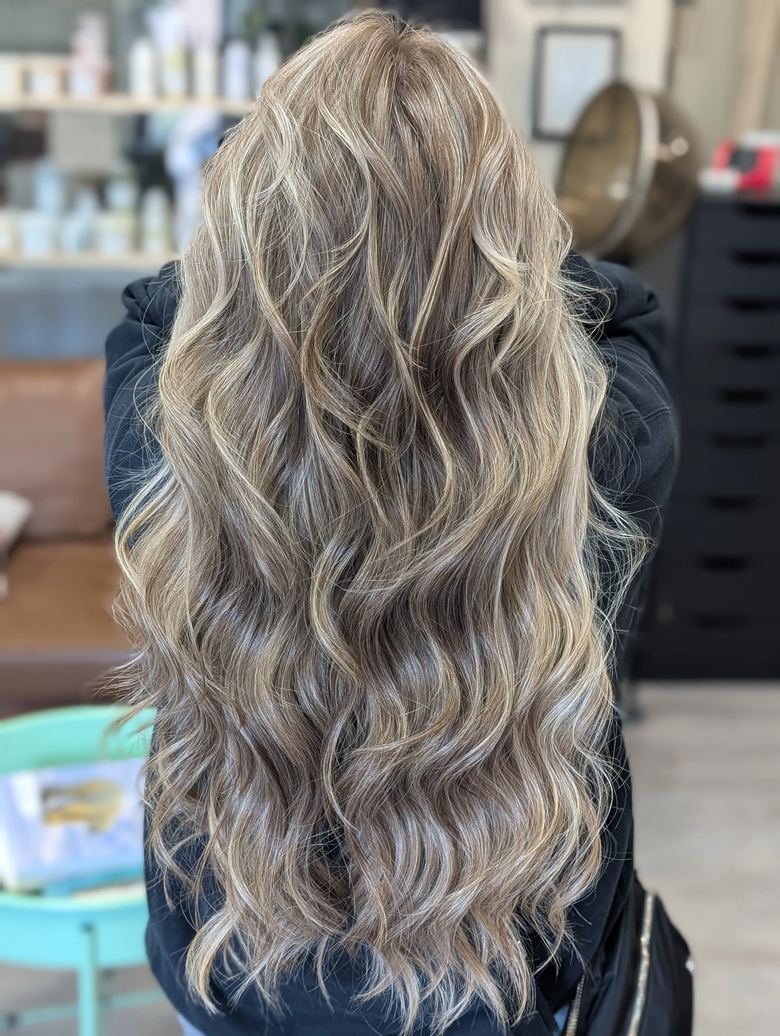 Back view of a woman with long, wavy blonde hair.