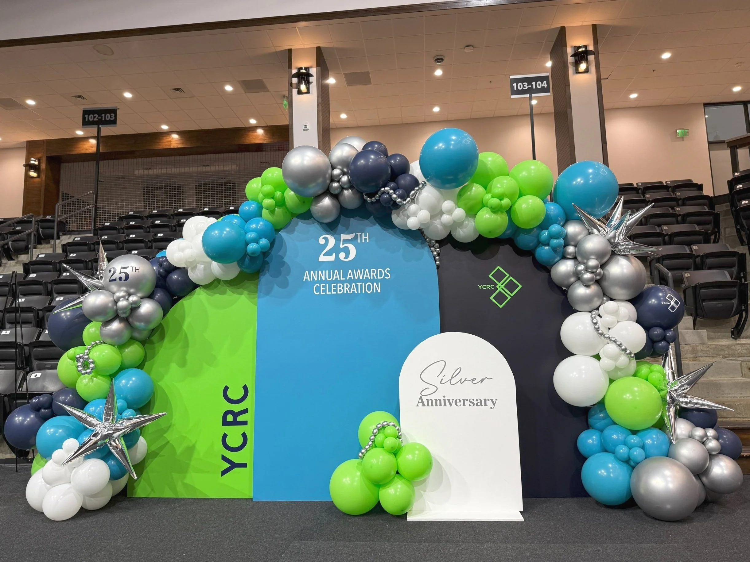 Balloon arch with blue, green, white, and silver balloons celebrating YCRC's 25th annual awards ceremony and silver anniversary