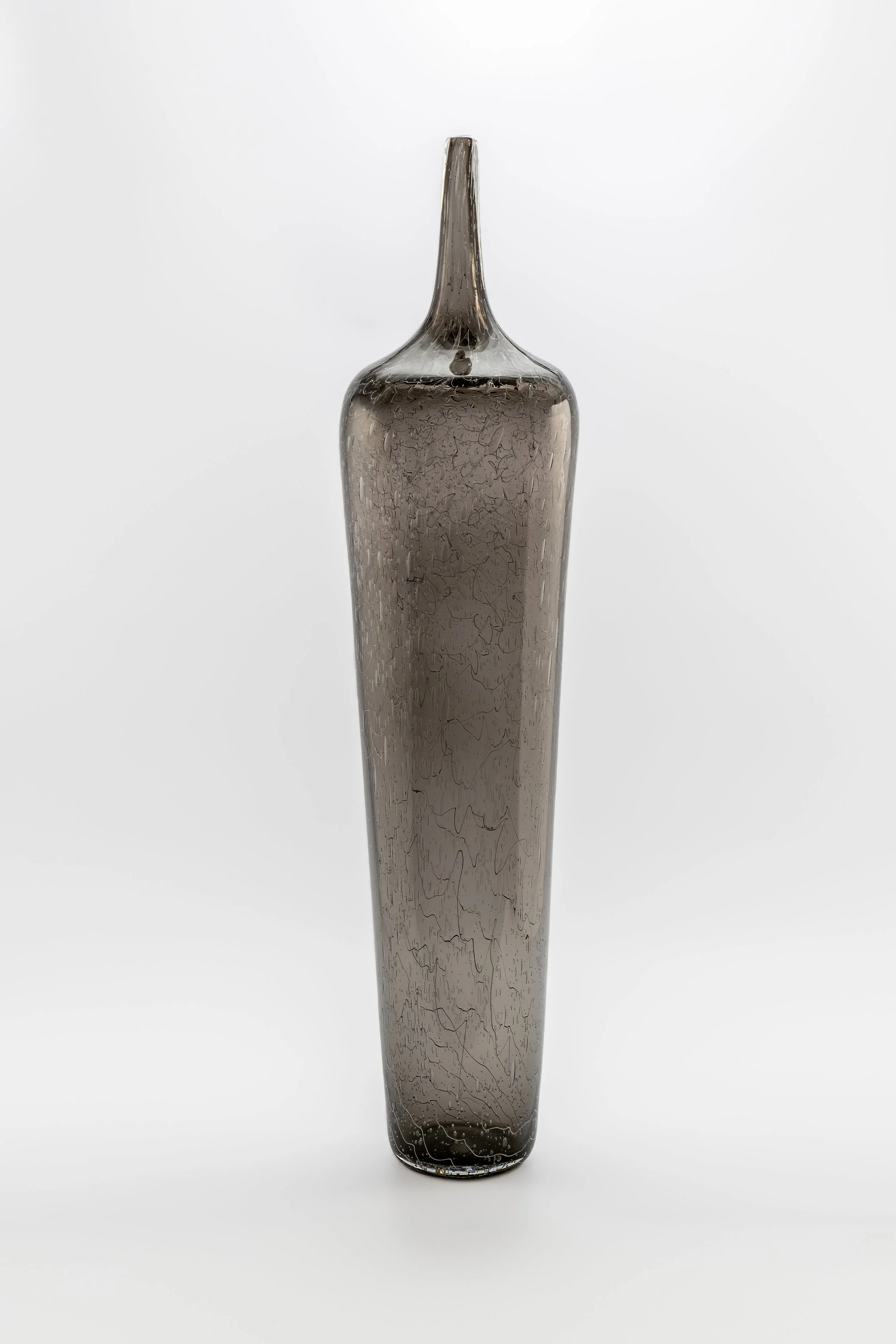 A tall, narrow, dark glass vase with a narrow neck and intricate crackle pattern, set against a plain white background.