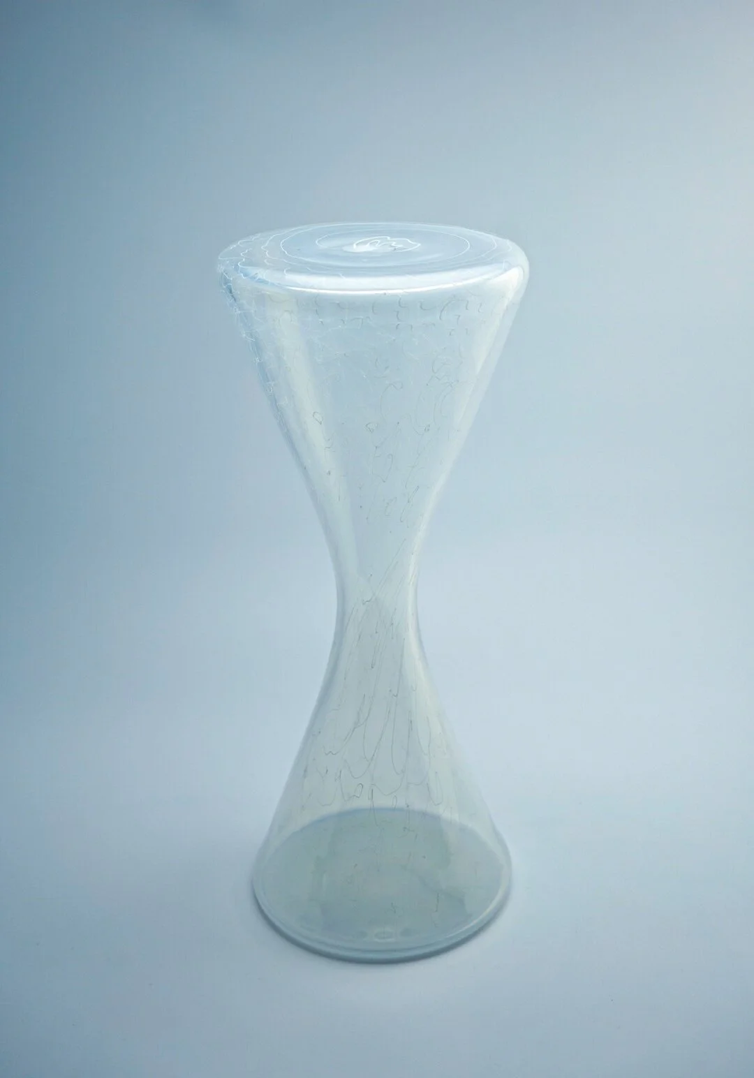 A clear glass hourglass with no sand, set against a plain light gray background.