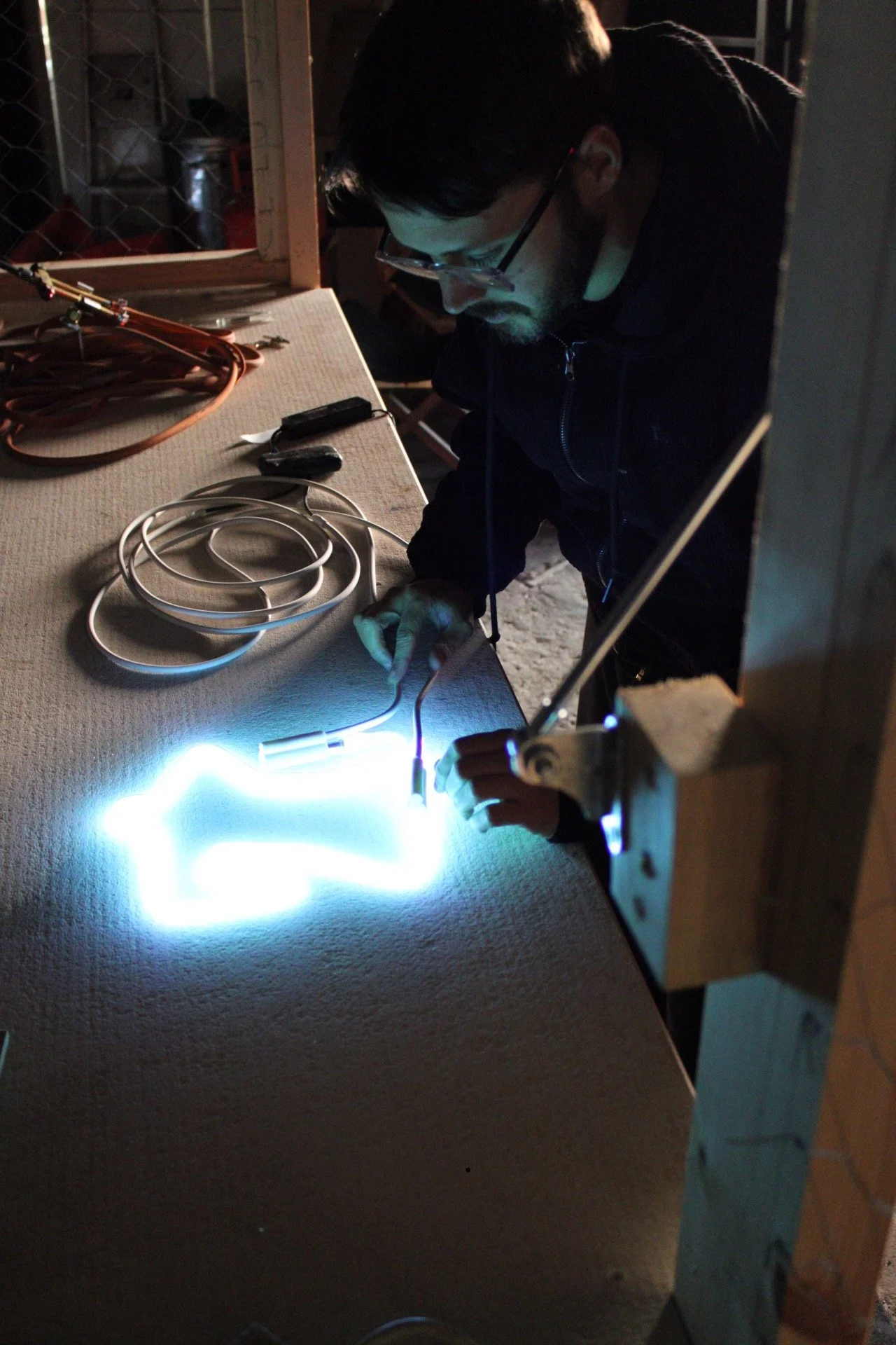 Real hand-bent glass neon tubing illuminated during the neon sign making process.