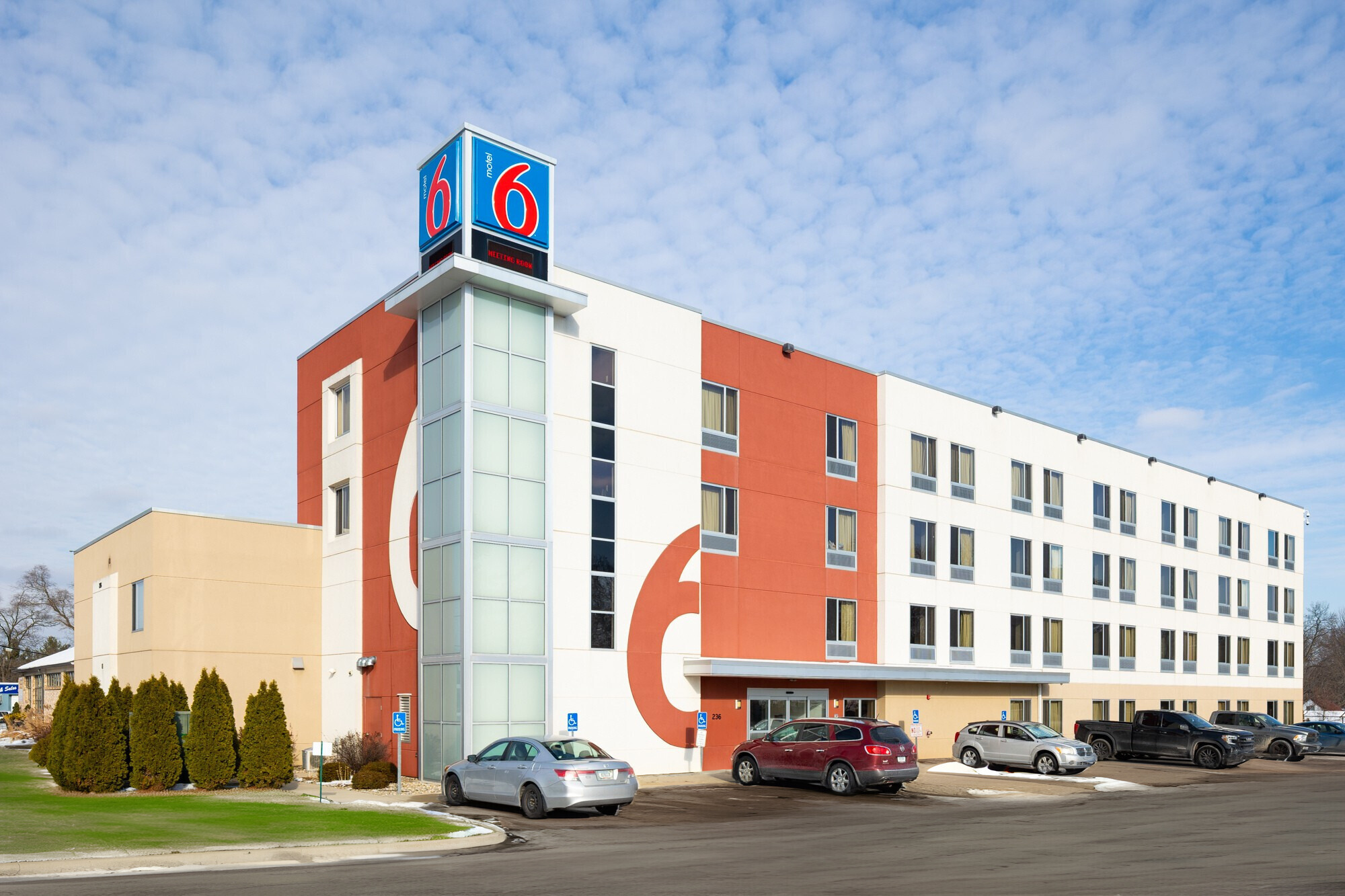 Exterior of a hotel building with lit windows, trees, streetlights, an American flag, and a sign that reads 'Embassy Suites' at night.