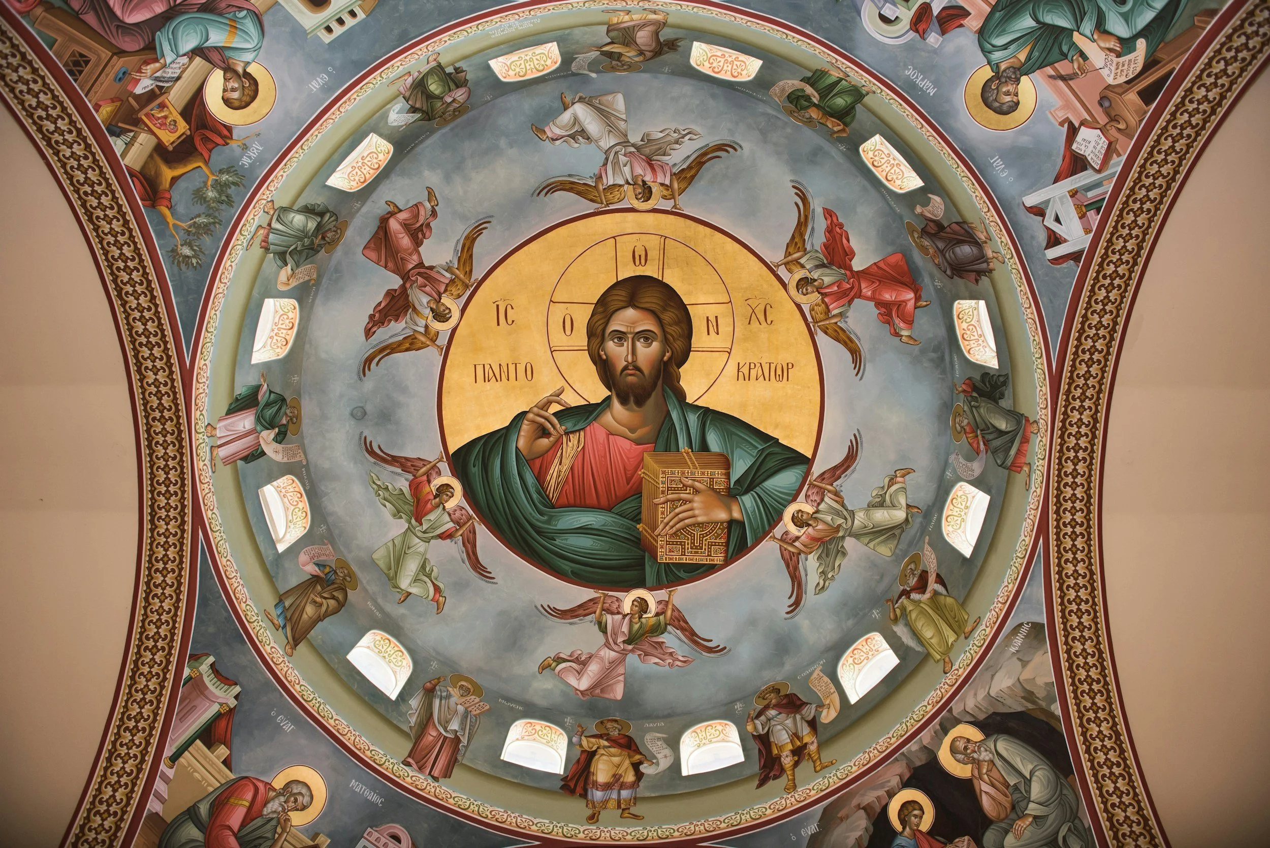 Orthodox church ceiling with Christ Pantocrator icon surrounded by angels and apostles, showcasing religious art and decorative patterns.