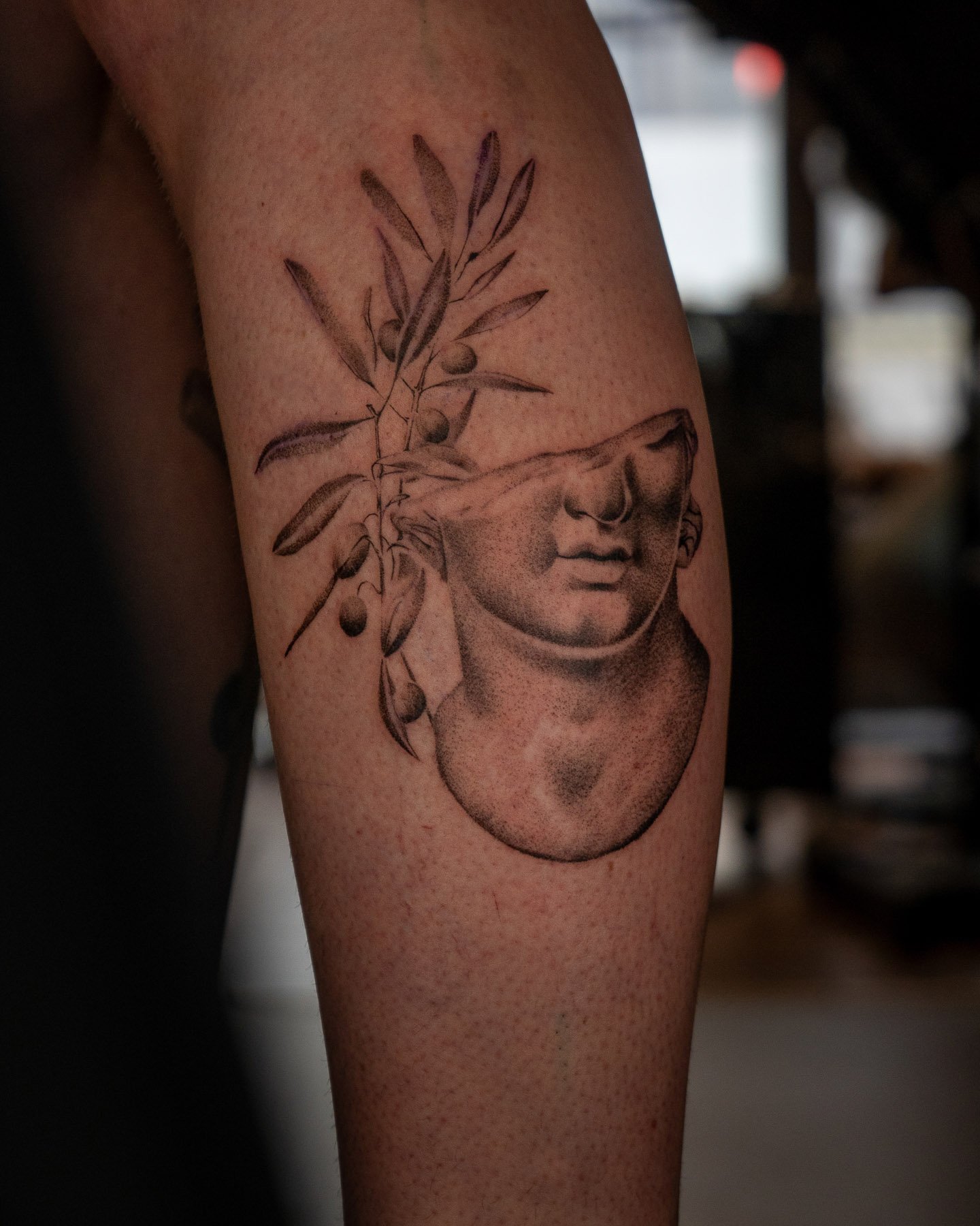 Tattoo of a headless statue with olive branches