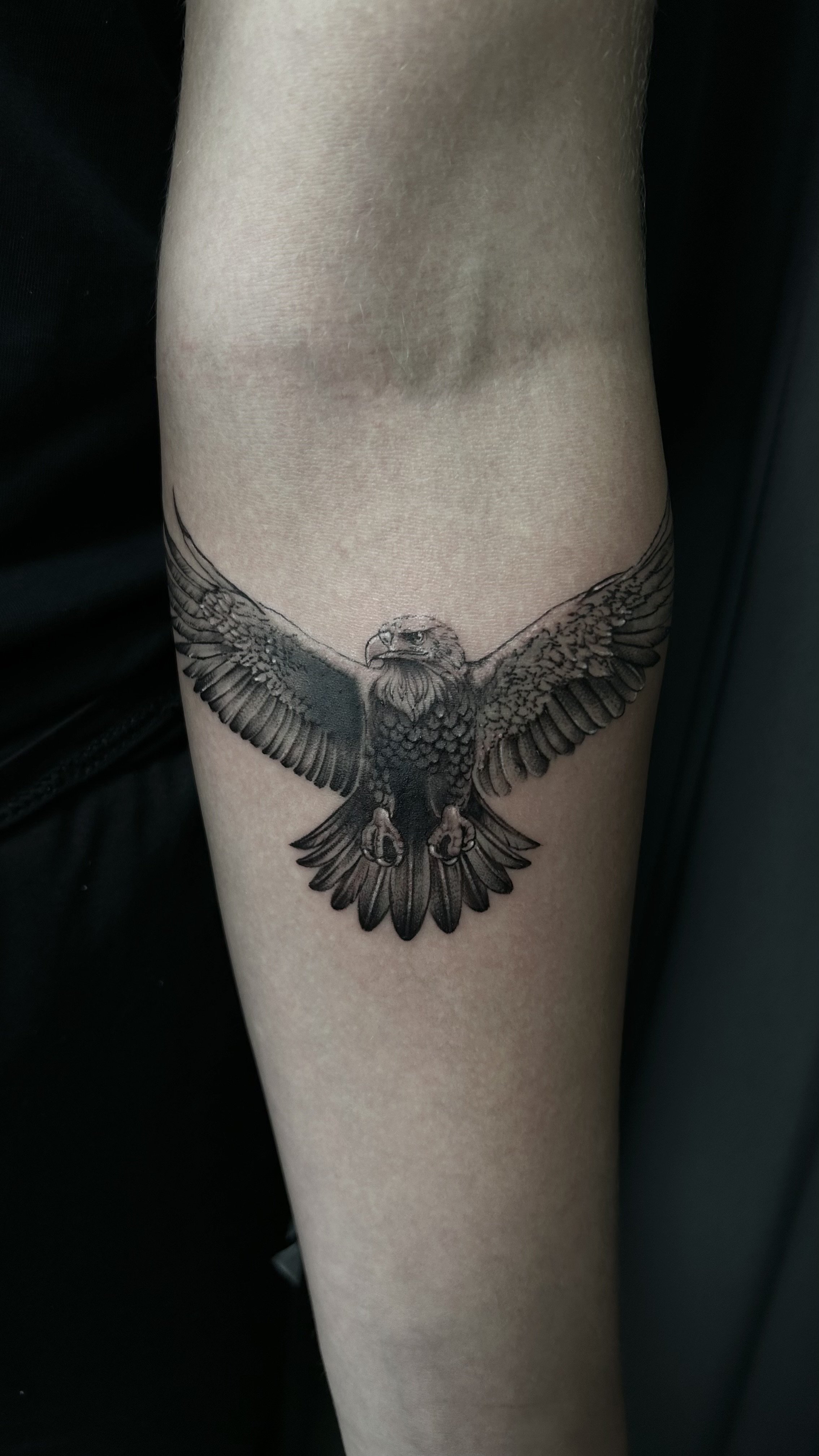 En tatuering av en örn med utsträckta vingar på en arm.