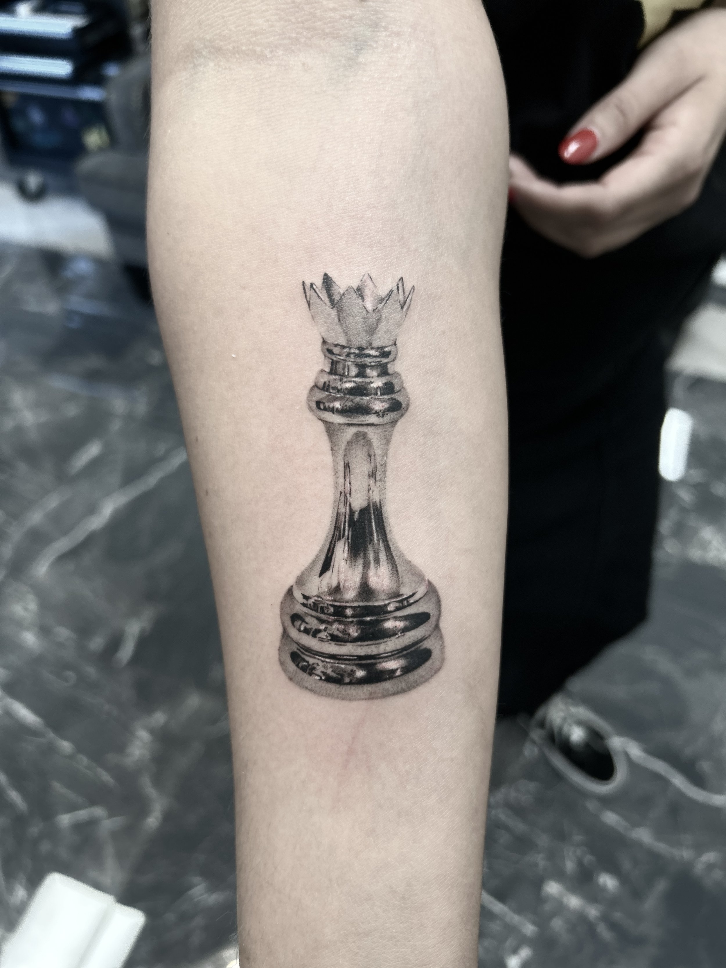 Tatuerad bild av en schackkung på en underarm.