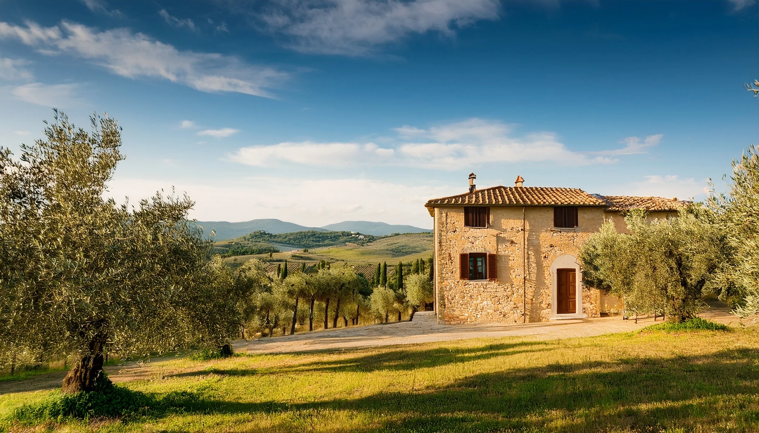 Ein Bauernhaus in einer ländlichen Landschaft, umgeben von Olivenbäumen und grünen Hügeln unter blauem Himmel.