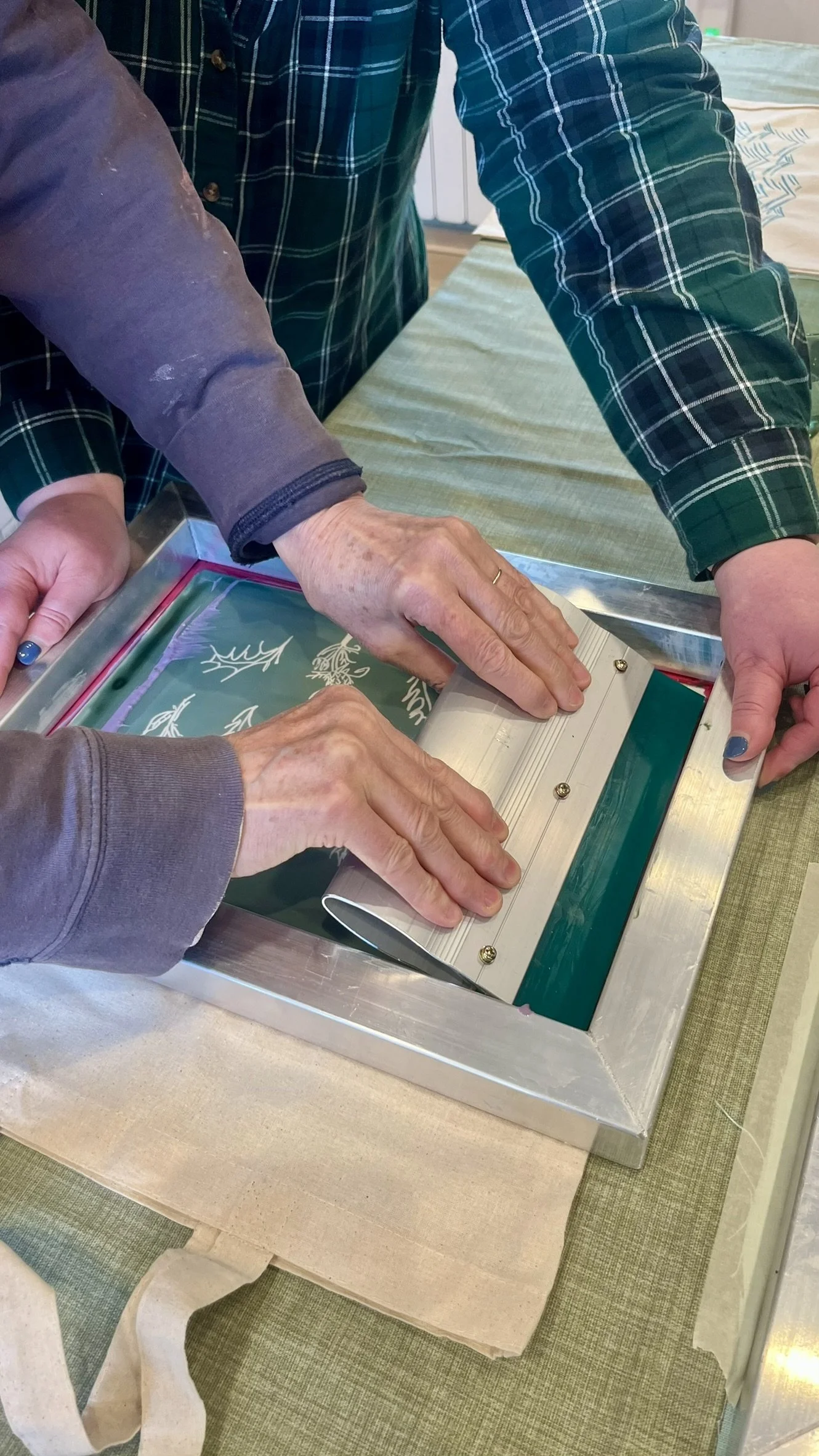 Two sets of hands working on a screen printing project.