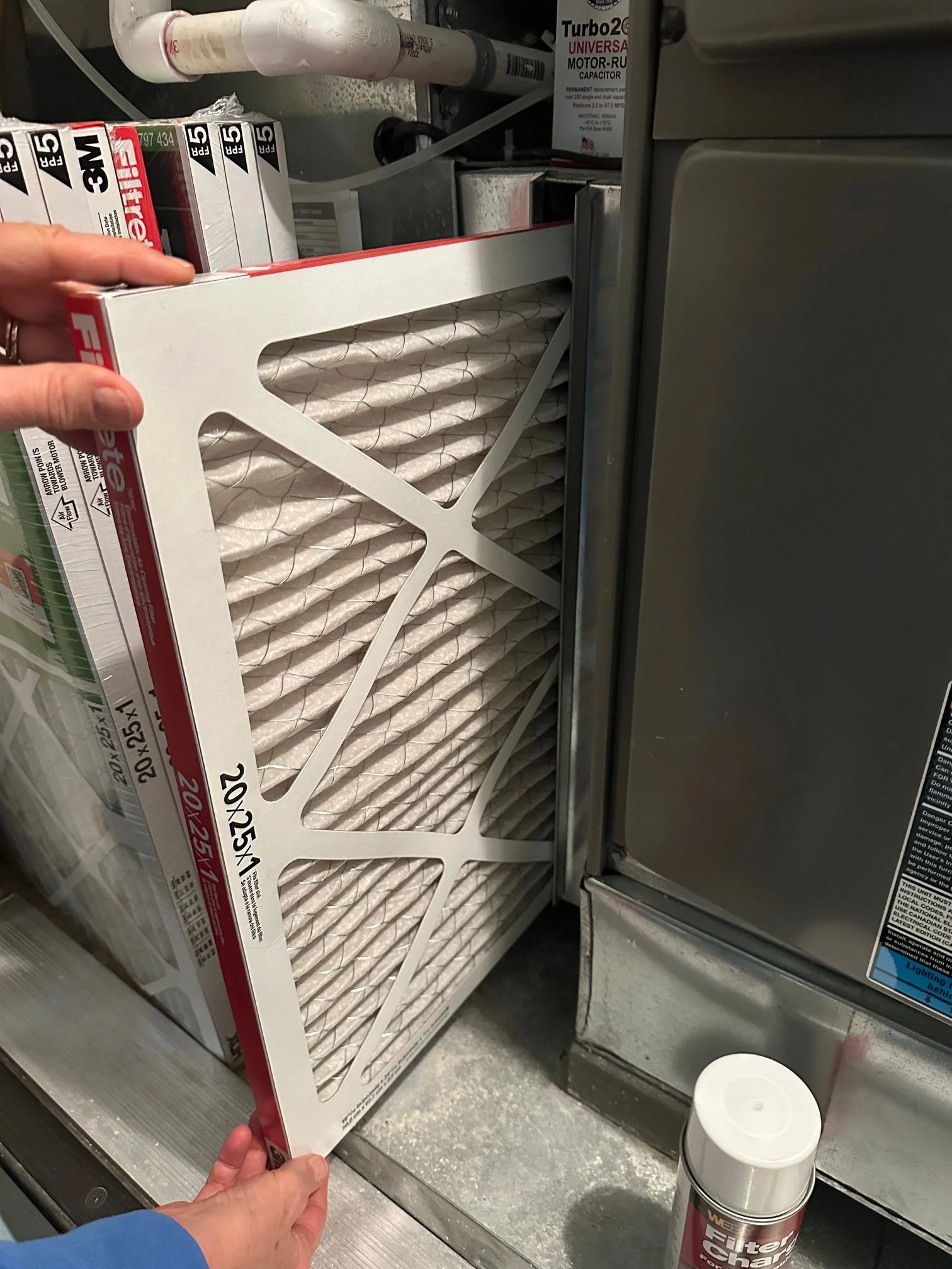 Homeowner changing HVAC air filter in new Kansas City home during winter maintenance routine