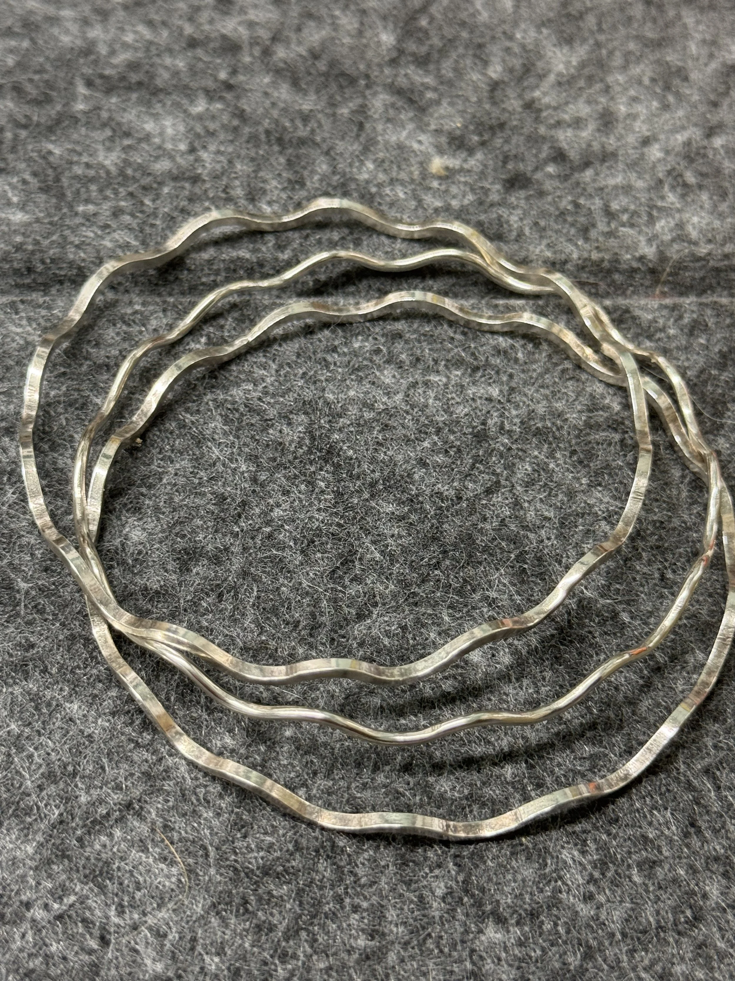 A selection of three slim wavy silver bangles