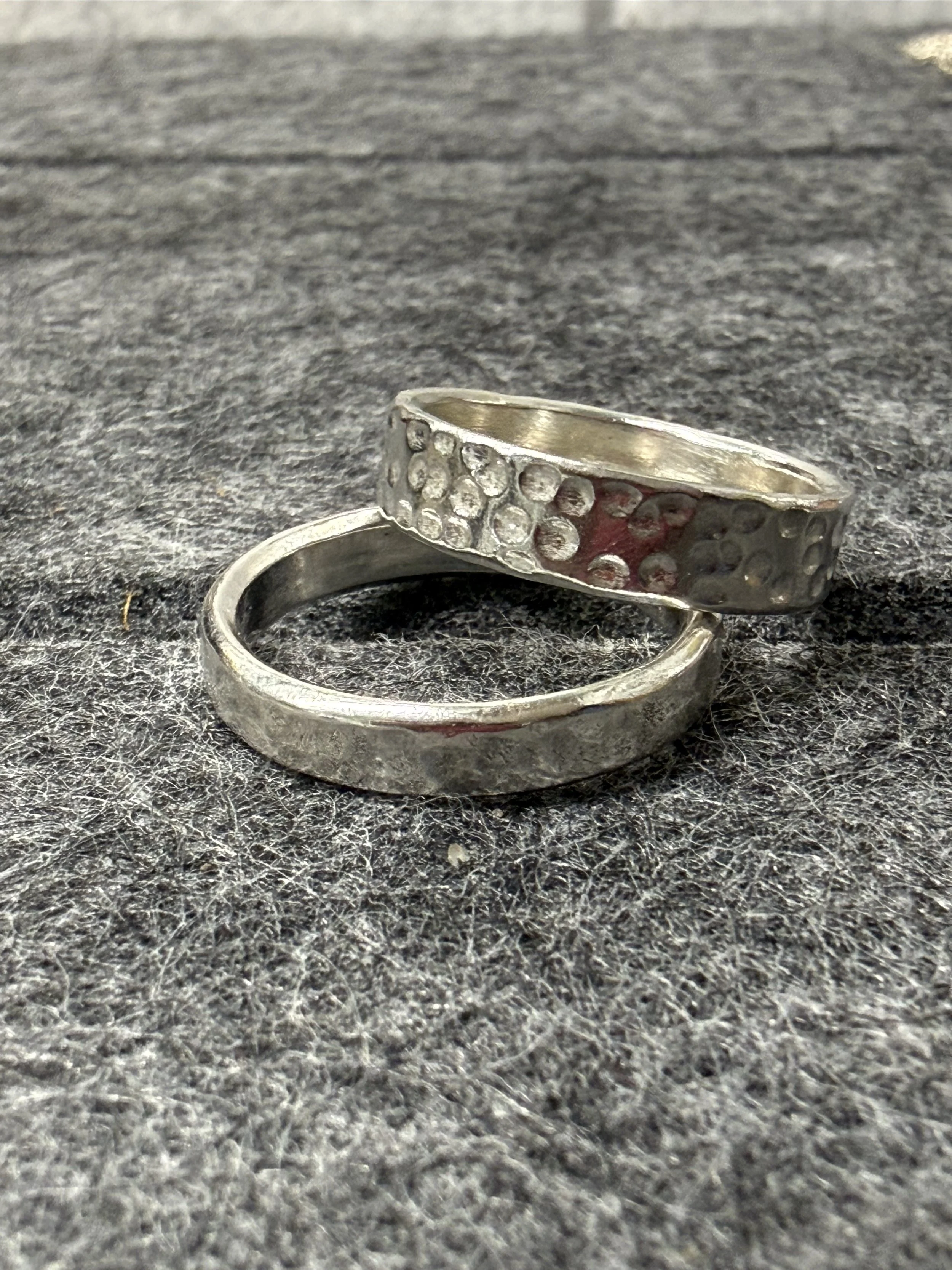 A picture of two silver rings on a grey felt background