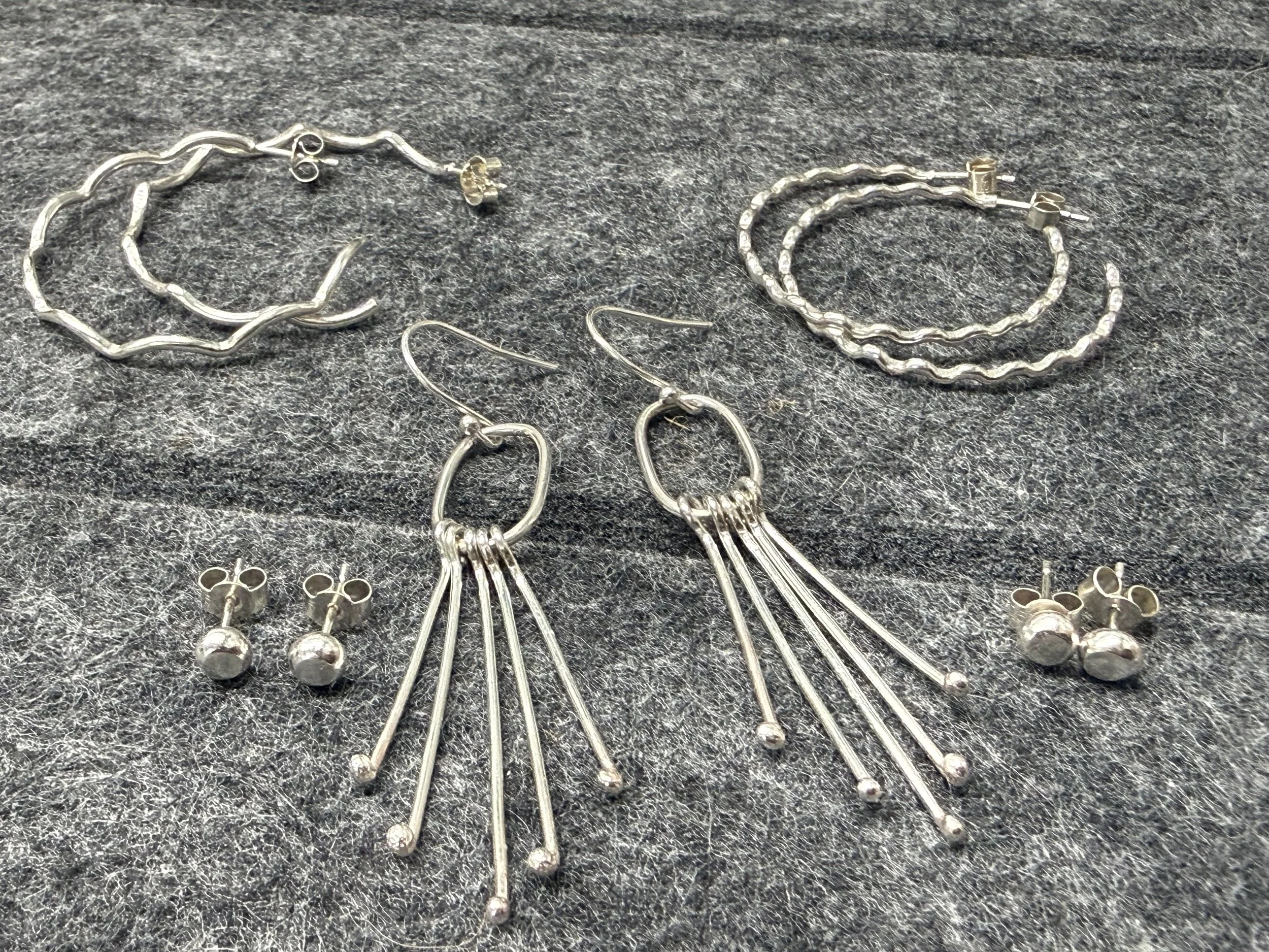 As selection of silver earrings including studs, hoops and long dangling earrings.