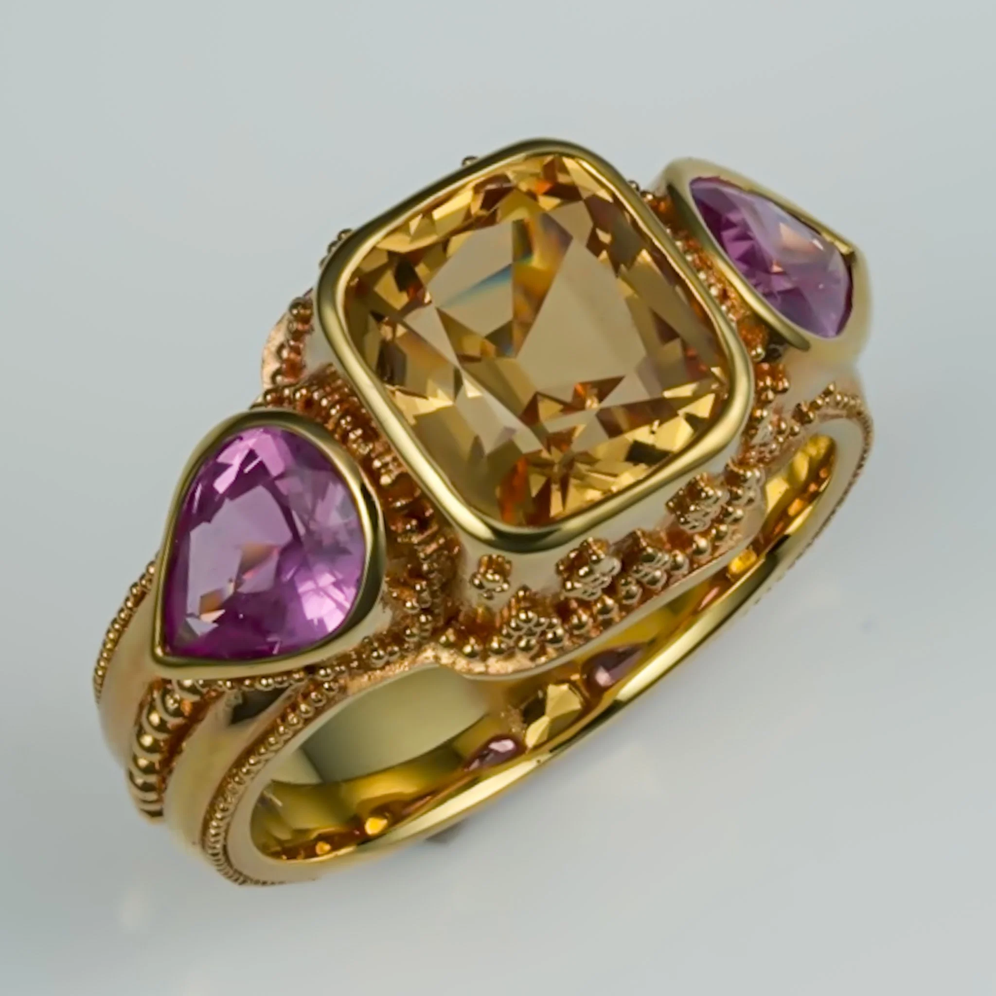 Hand-made 18k gold ring featuring an imperial topaz flanked by pink sapphire accents, designed and made by Nathan King.