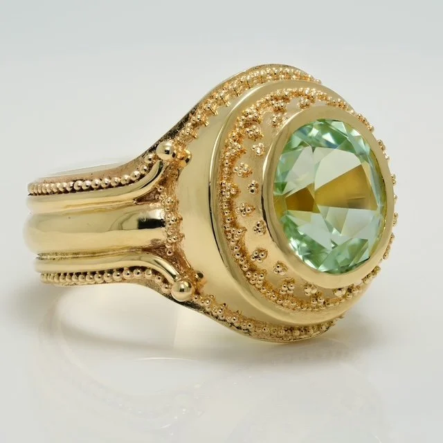 Hand-made 18k gold ring with an oval green gemstone, framed by Etruscan-inspired granulation.
