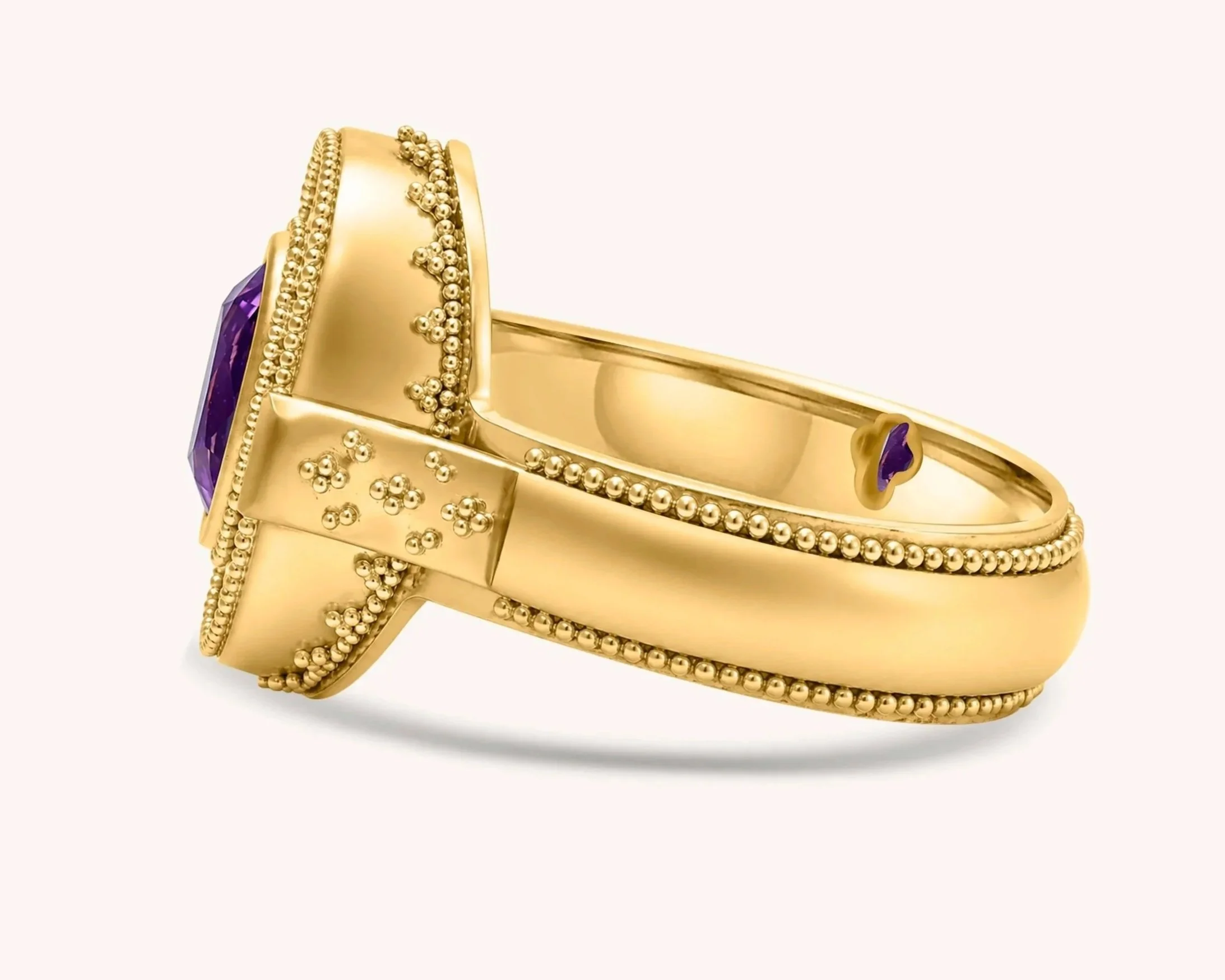Close-up side view of an 18k gold ring showing individually fused gold granules along the band and setting.