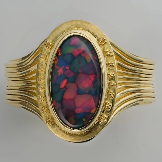 Hand-made 18k gold ring set with an flagstone opal, photographed against a clack ground to emphasize form and color