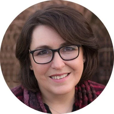 Beth Killion, writer, smiling wearing glasses, short dark hair, and a scarf, in a circular frame.