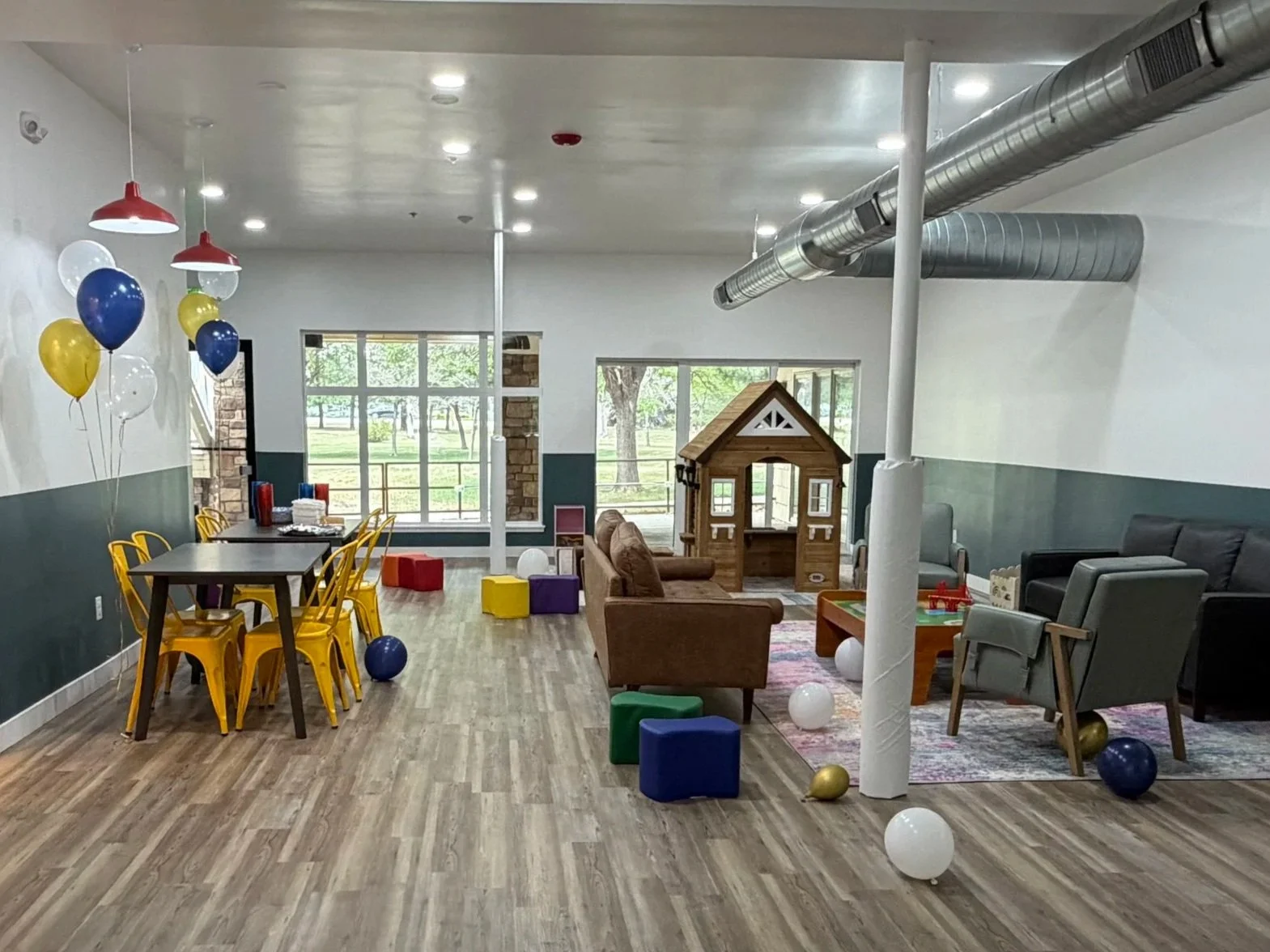 playspace with play house, tables, couches, blocks, and books