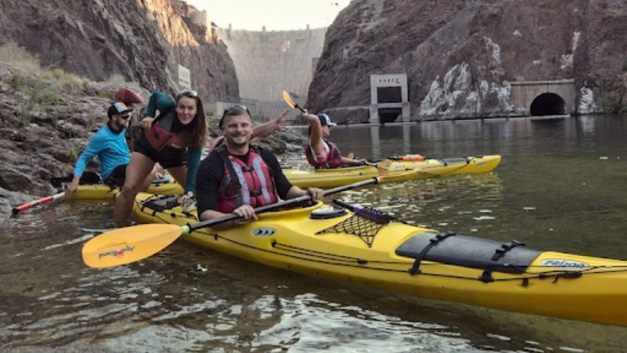 A group of people paddling kayaks on a calm river surrounded by lush greenery.