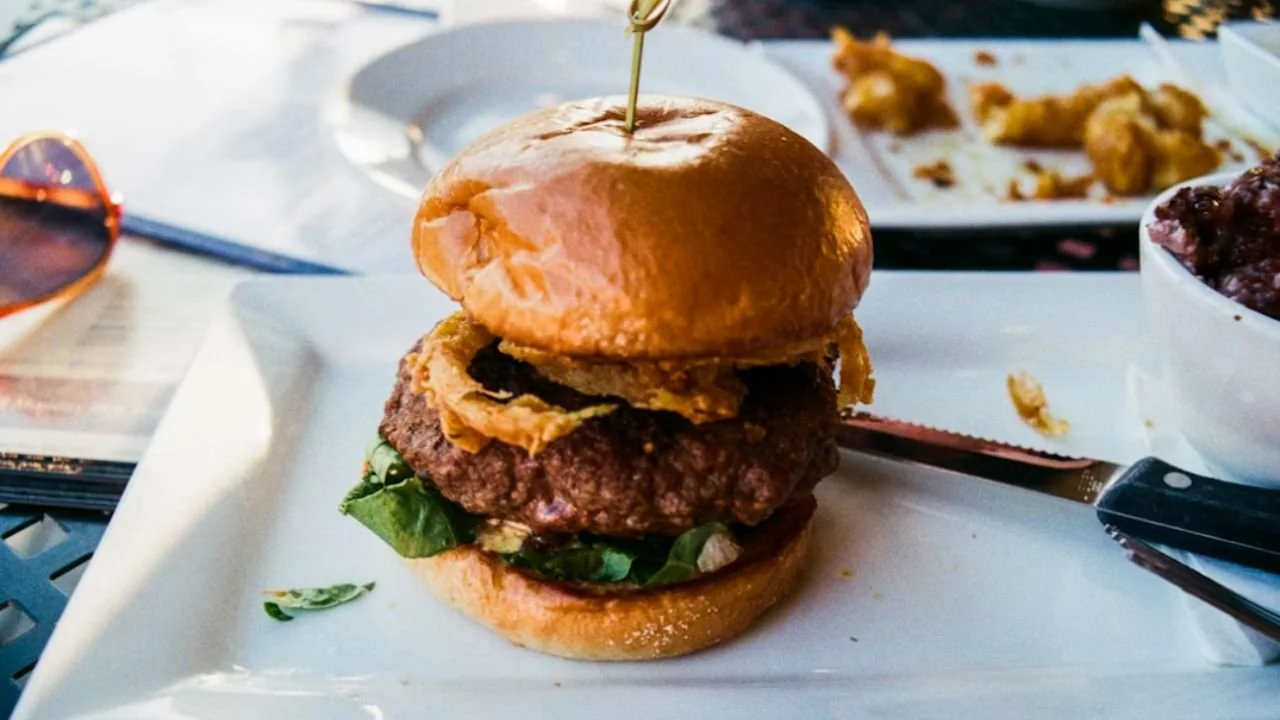Burger served on a plate with crispy onion rings and fresh greens in Minnesota’s Town Hall Station.