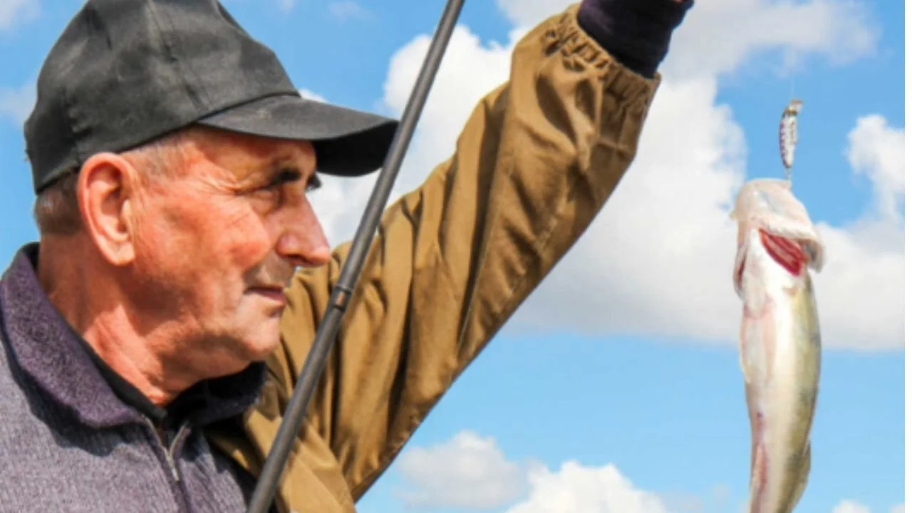 A senior citizen looking at a fish he caught.
