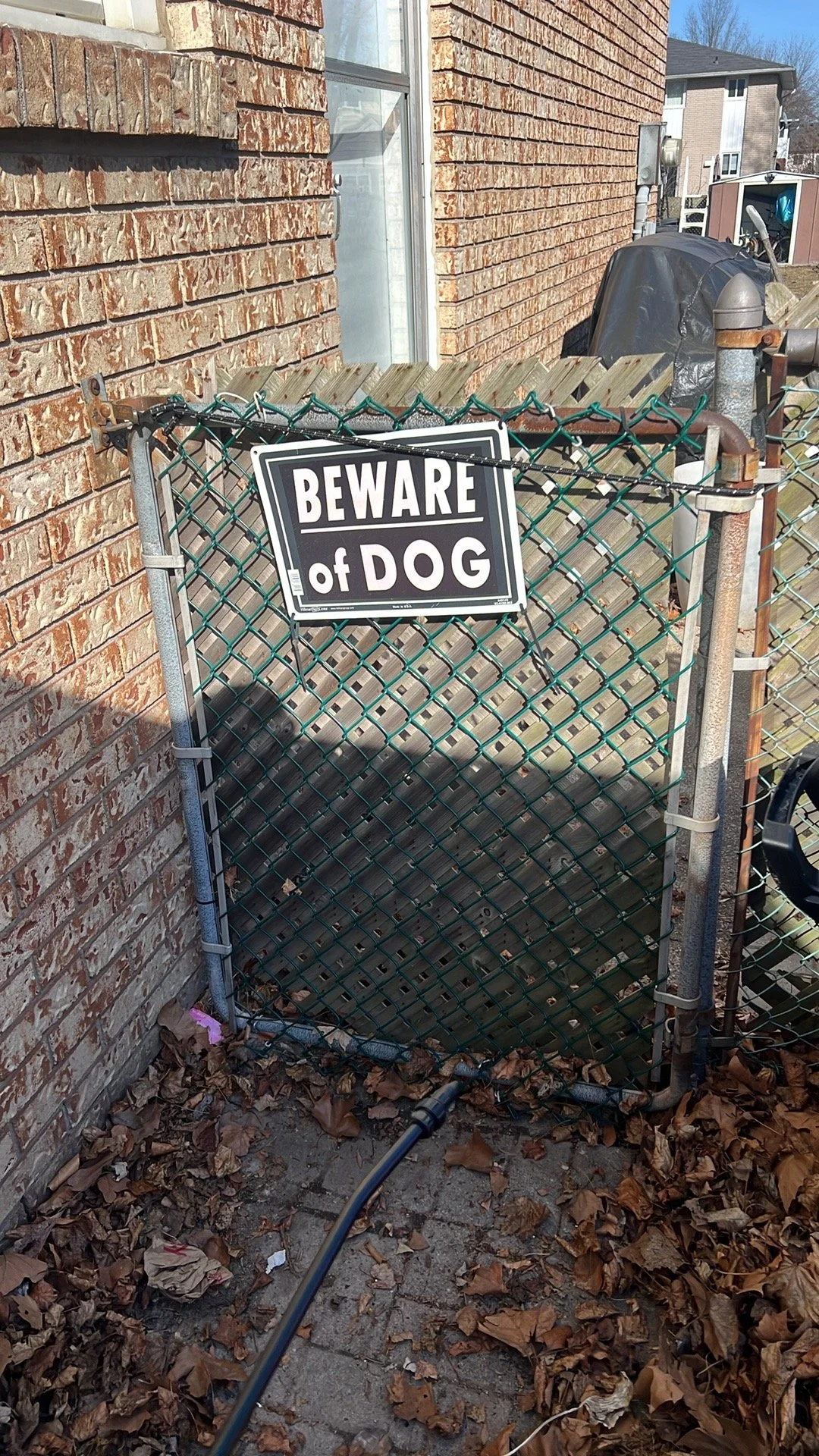 Chain-link fence with a 'Beware of Dog' sign attached.