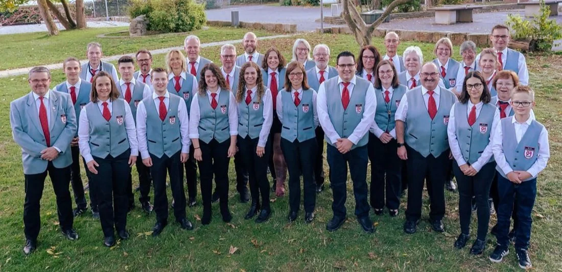 Gruppe von Menschen in formellen blauenuniformierten Outfits, die für ein Foto im Freien posieren.