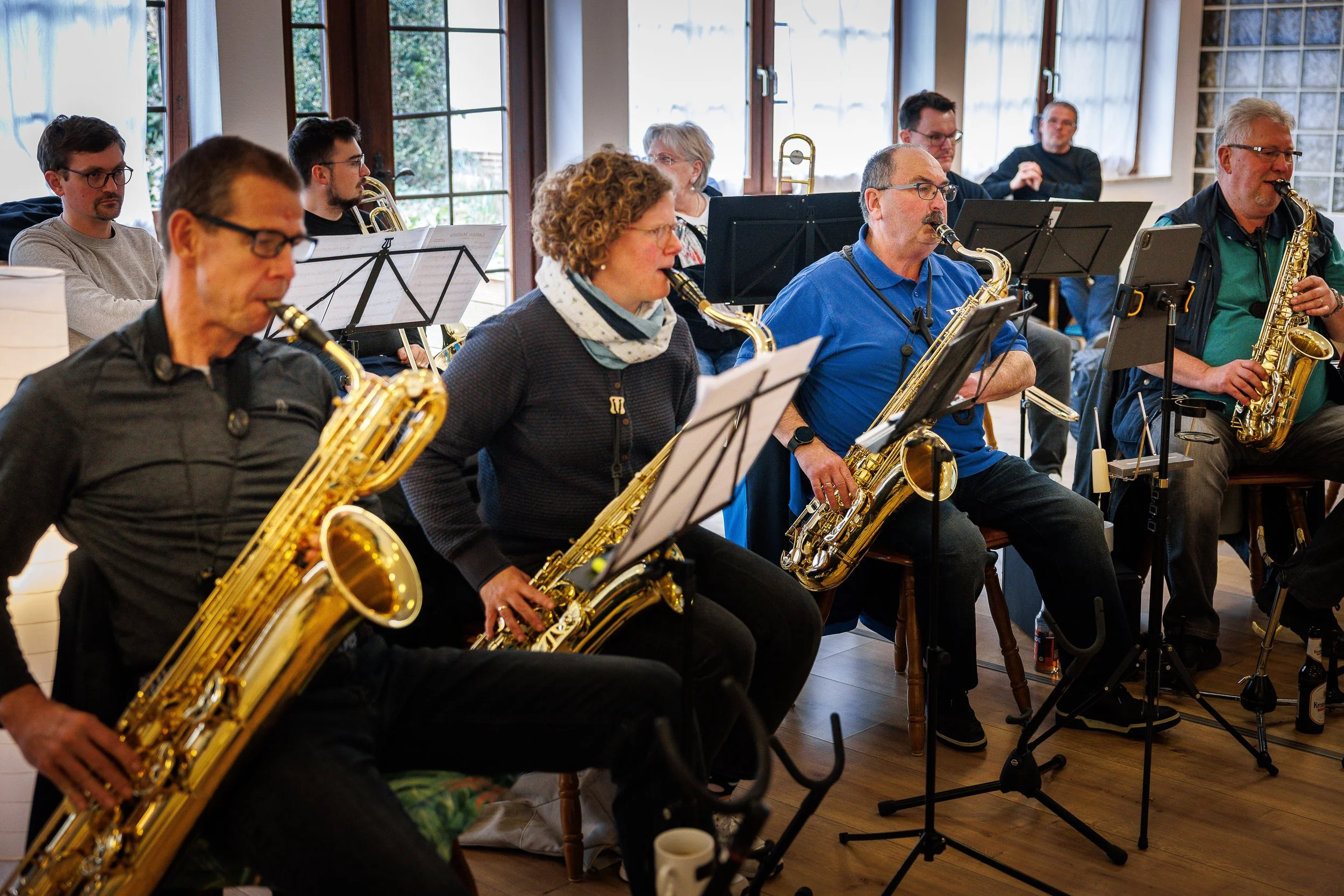 Eine Gruppe von Musikern, die Saxophone spielen, während sie in einem Raum mit großen Fenstern üben.