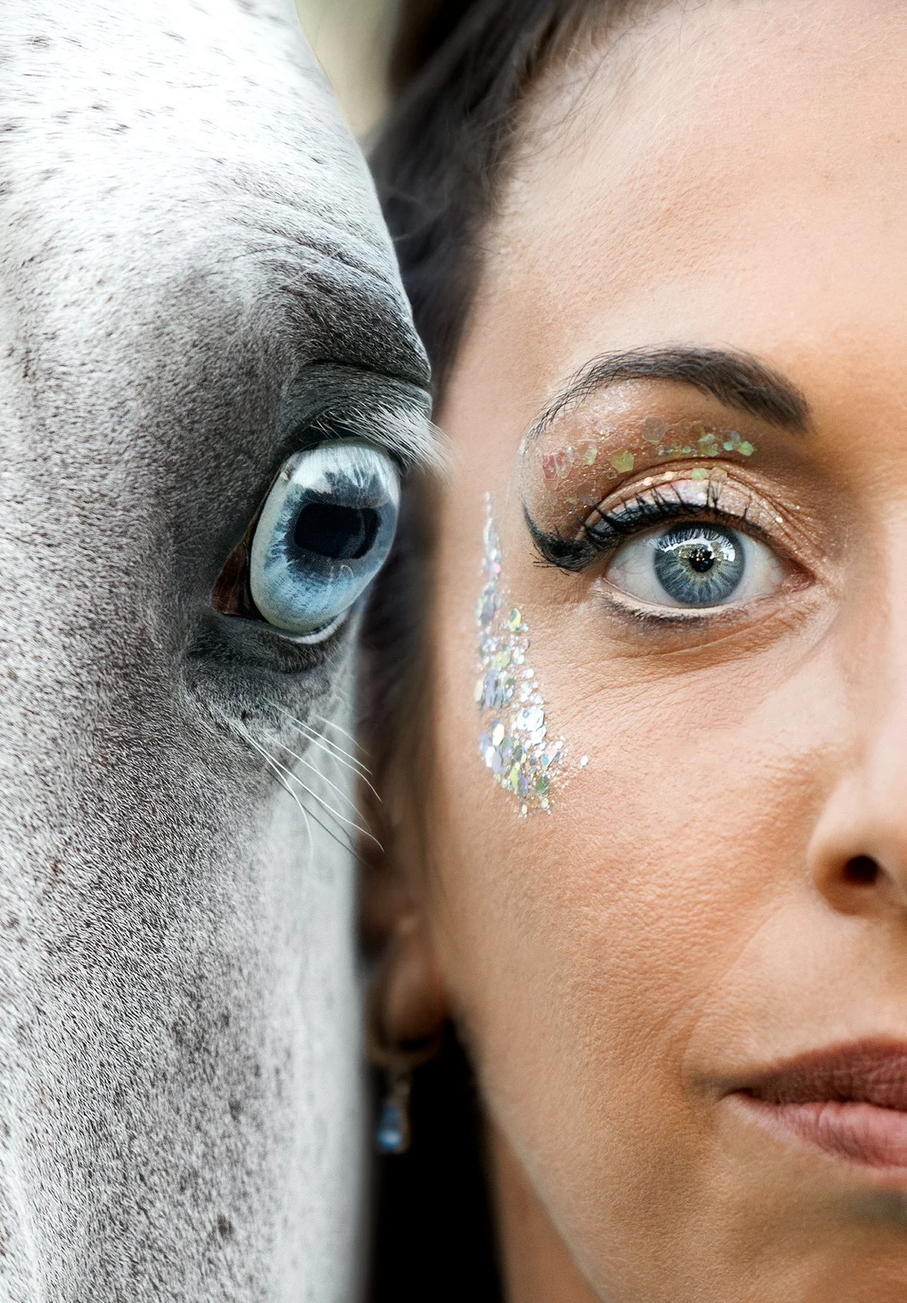 Photo d'une femme avec maquillage brillant et paillettes sur la joue, côte à côte avec un cheval dont l'œil est visible en gros plan.