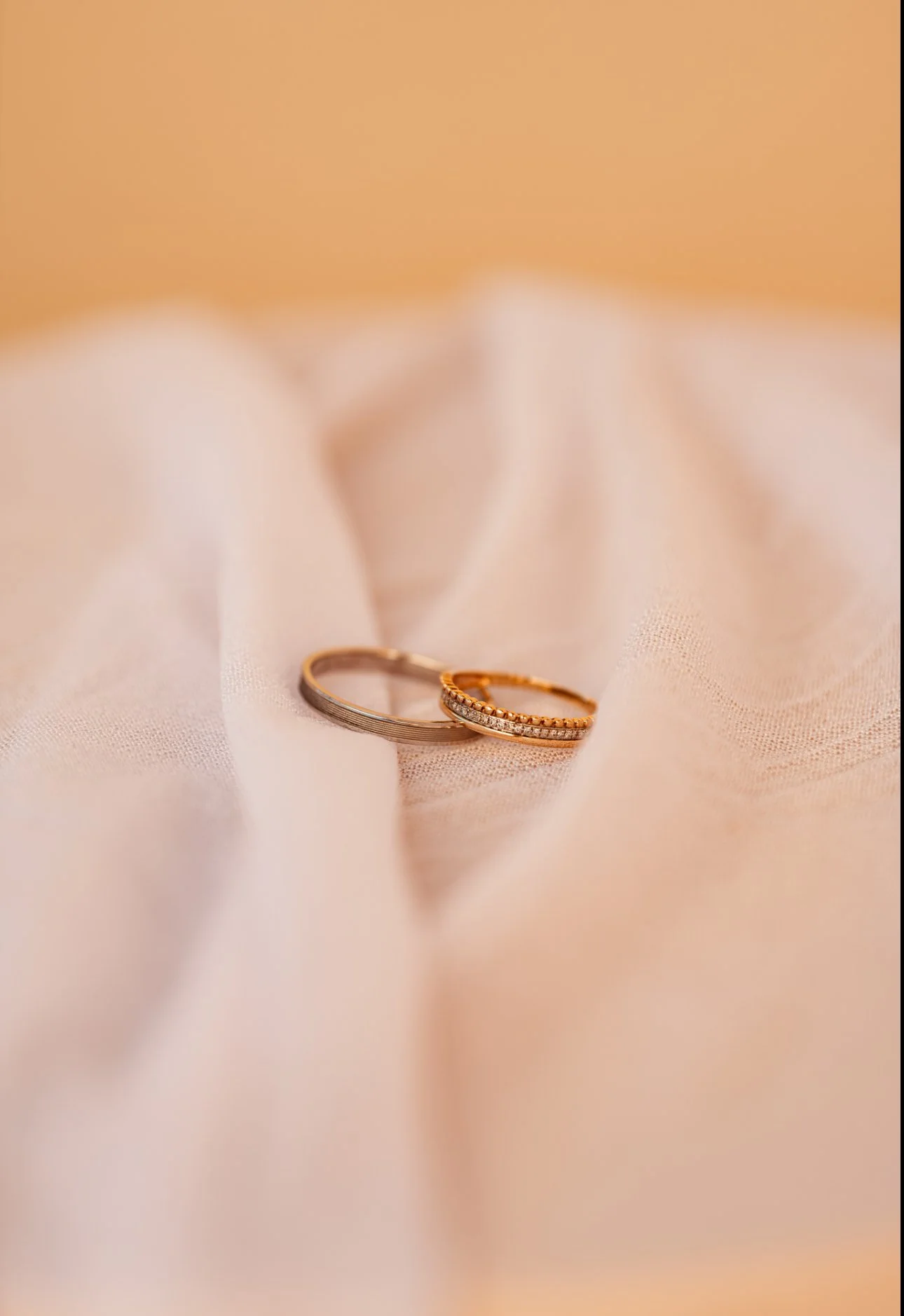 Deux bagues, une en or avec des diamants et une en argent, reposant sur un tissu beige