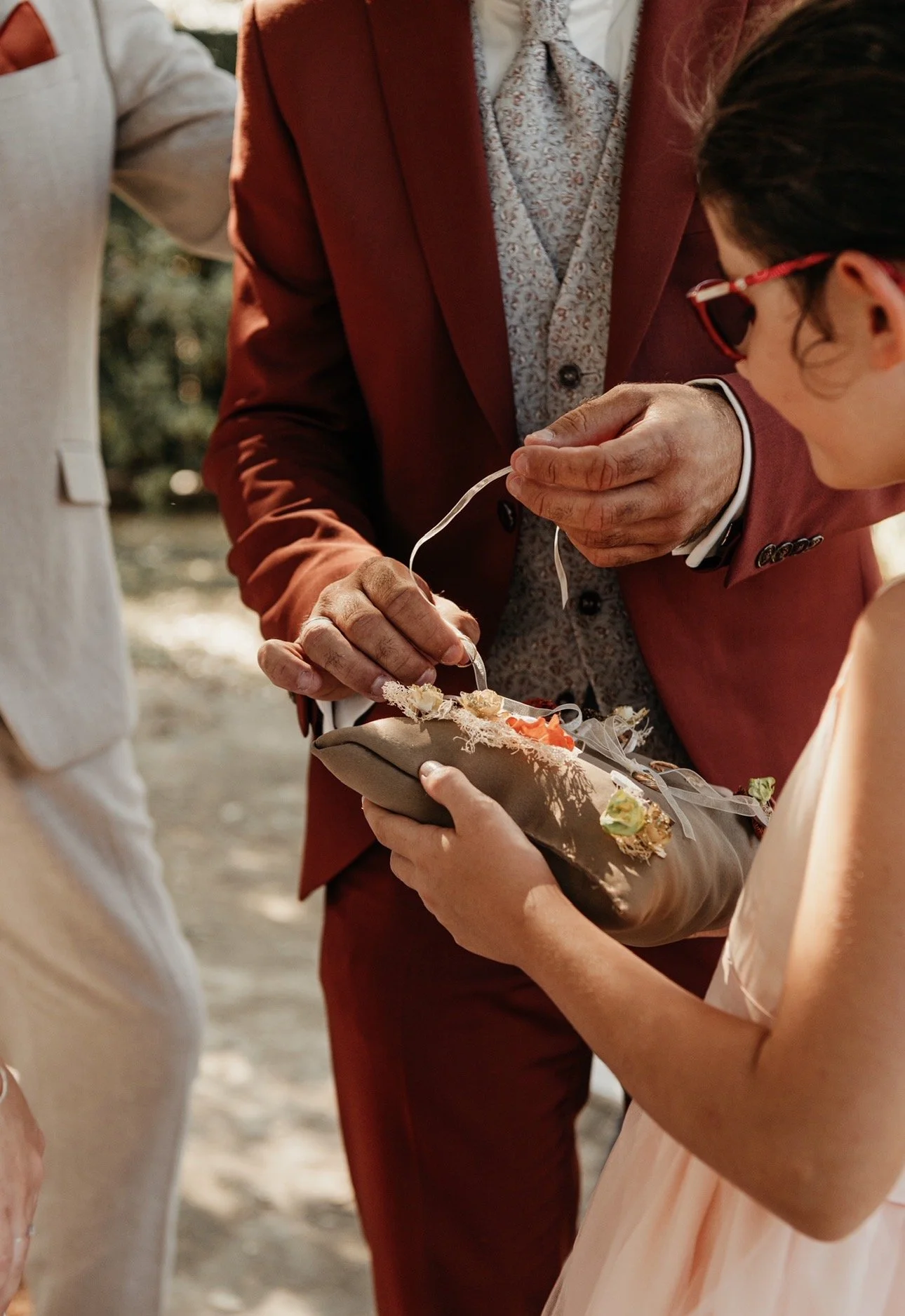 Une personne en costume rouge-offre un anneau à une jeune fille lors d'une cérémonie en plein air.