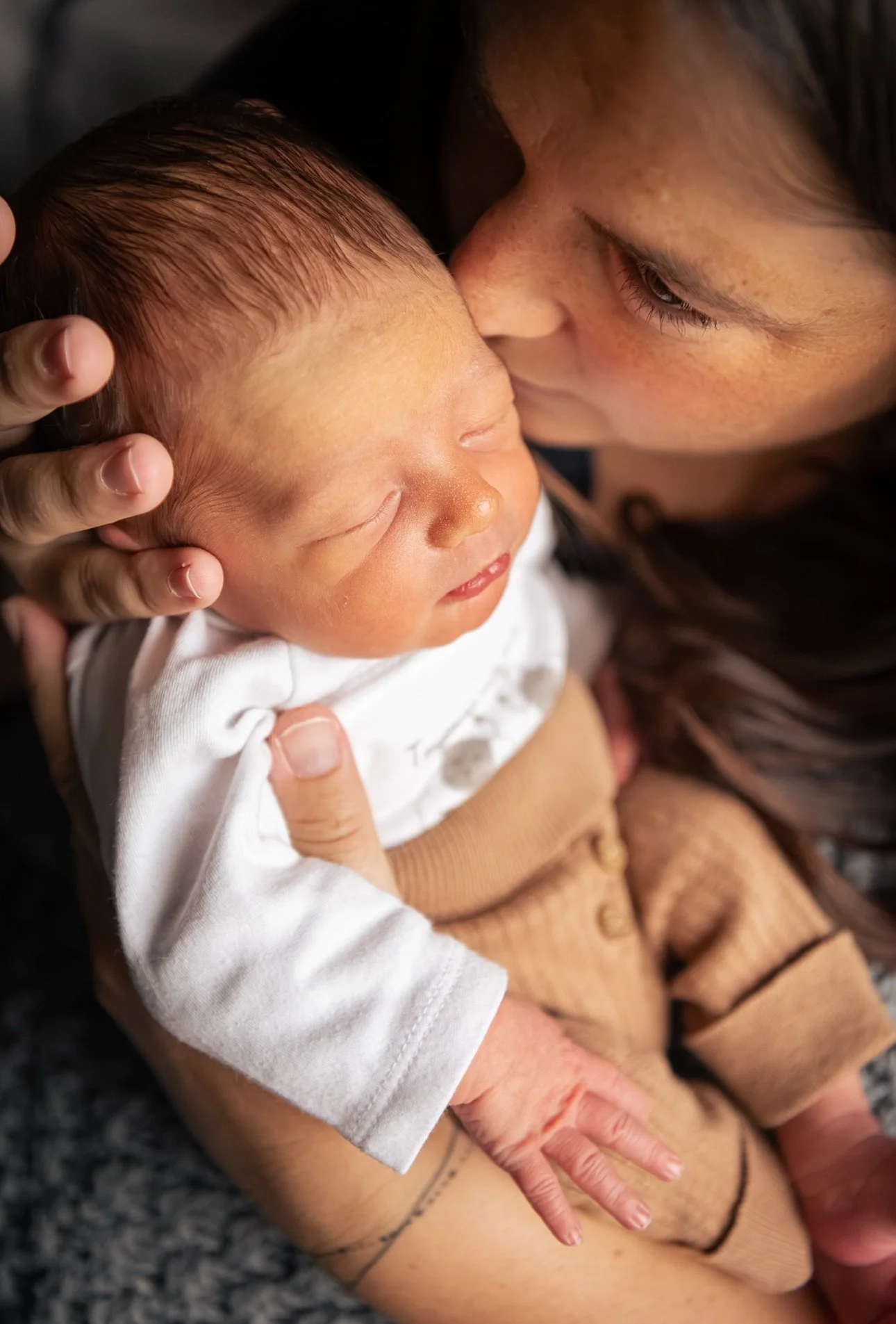 Une femme tient un nourrisson dans ses bras, l'enlaçant tendrement dans une atmosphère chaleureuse.