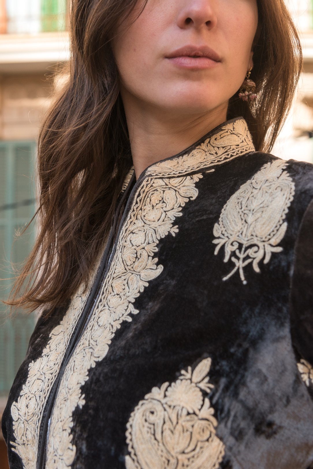 Woman wearing an intricately embroidered jacket with floral patterns.