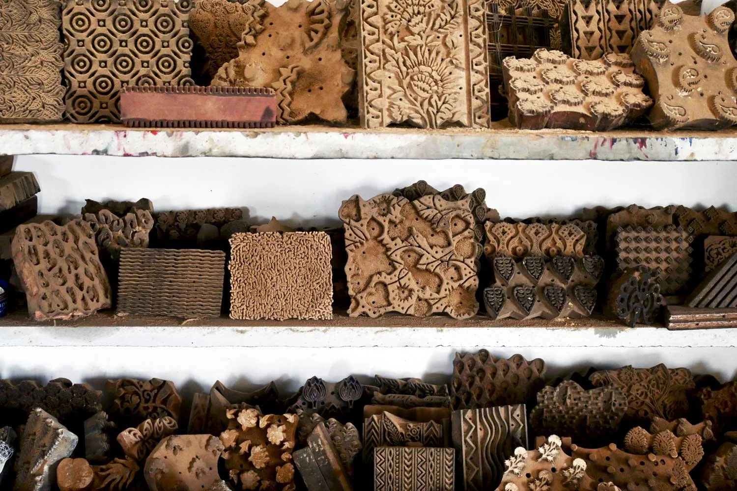 Shelf with various wooden block printing stamps, intricately carved with diverse patterns and designs.