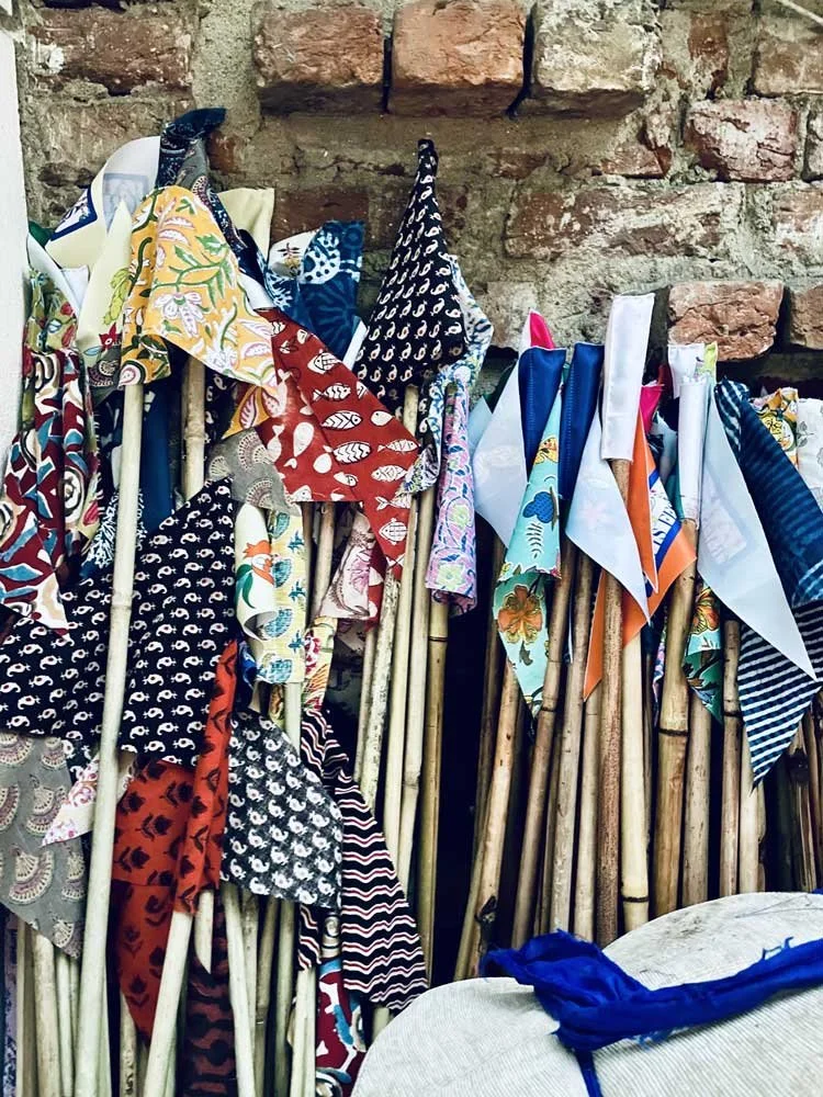 Colorful fabric flags on wooden sticks against a brick wall