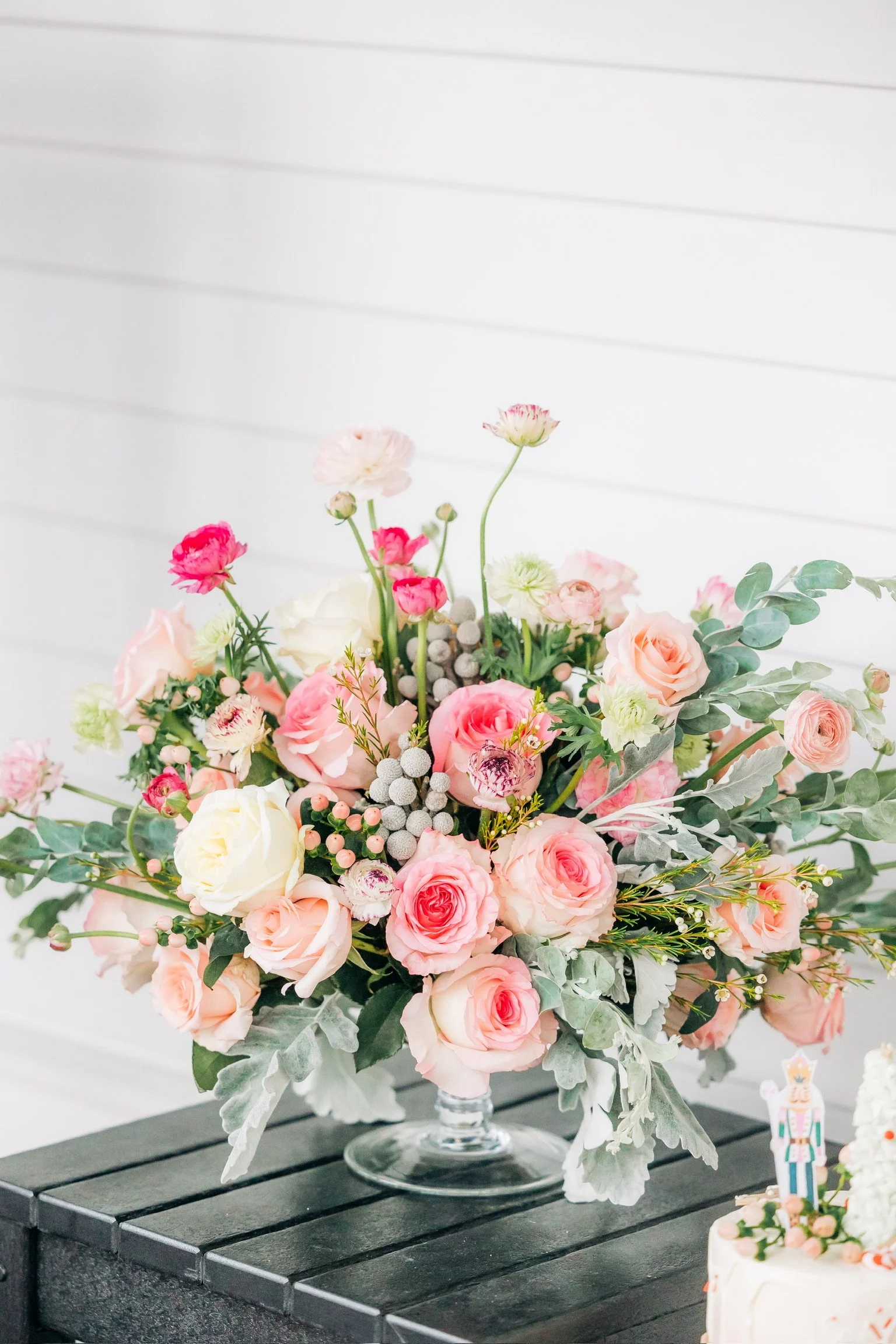 Elegant floral arrangement with pink and white roses, eucalyptus leaves, and assorted blossoms on a dark wooden table.