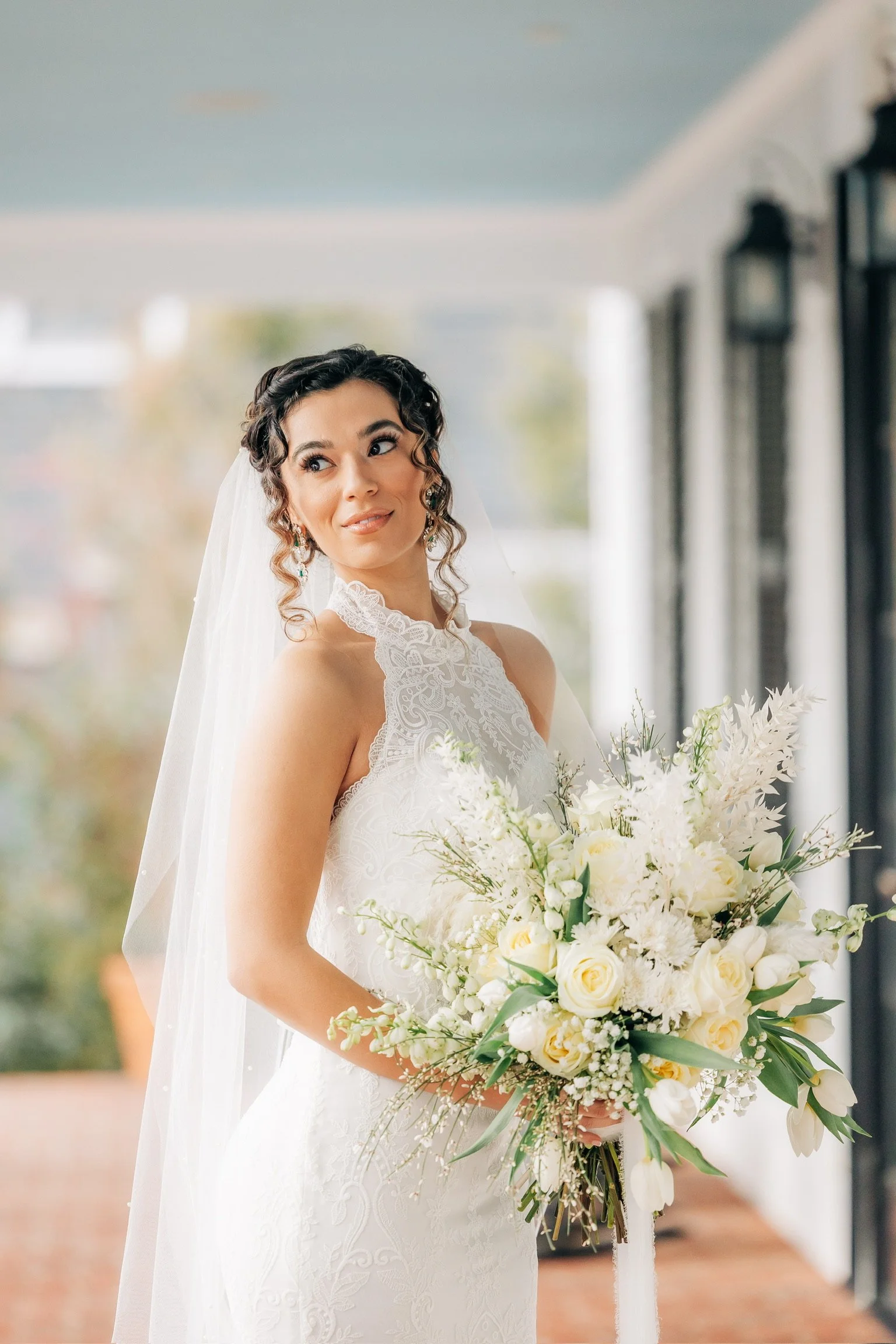 Bride in a lace wedding dress with a bouquet of white and cream flowers.