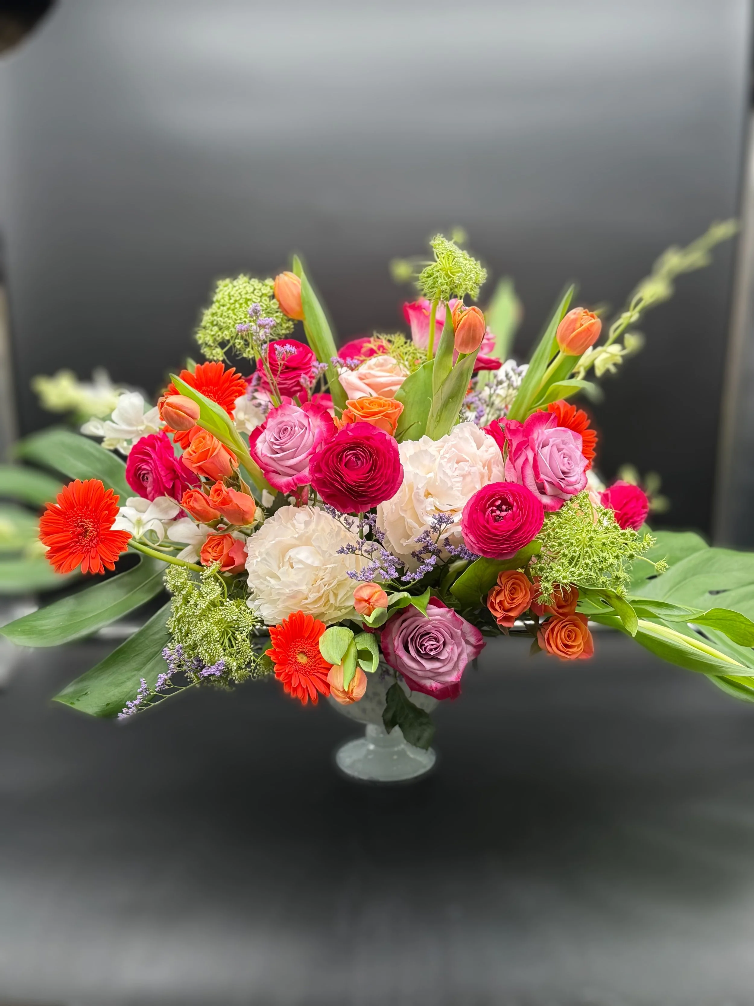 Colorful floral arrangement with roses, tulips, and greenery in a vase.