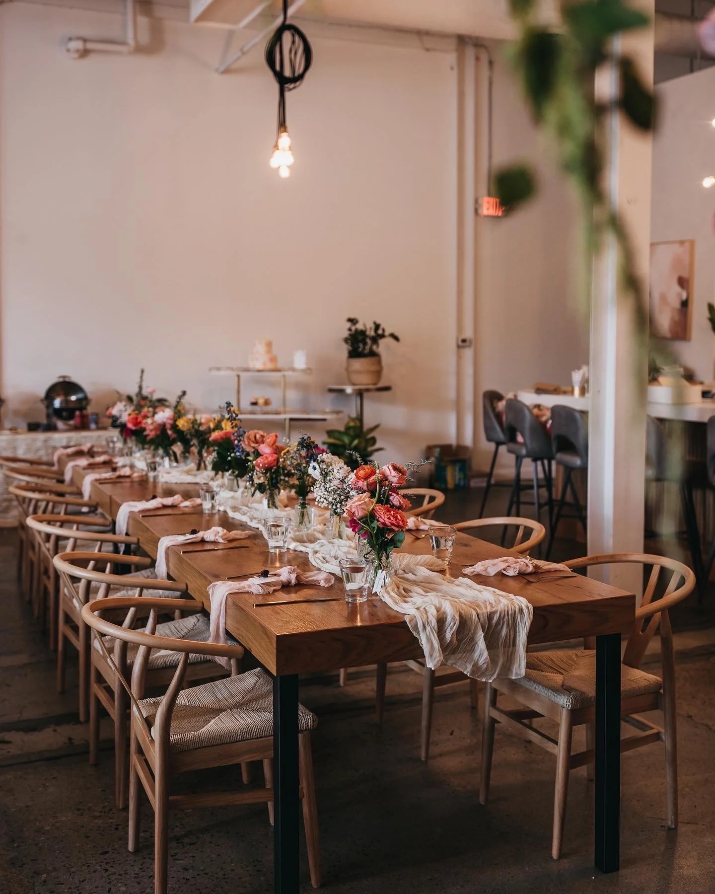 Elegant dining setup with a long wooden table decorated with flowers and tableware