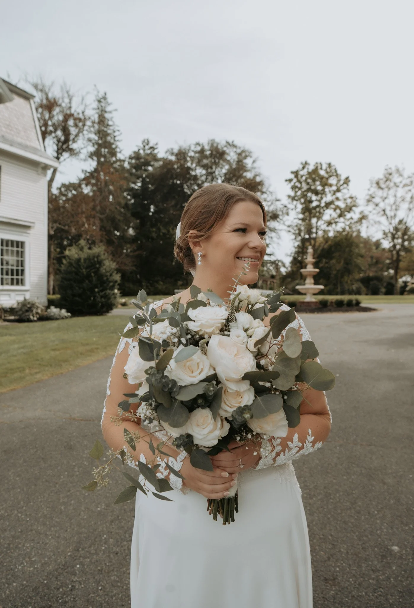 Bride holding a bouquet of white roses outdoors
