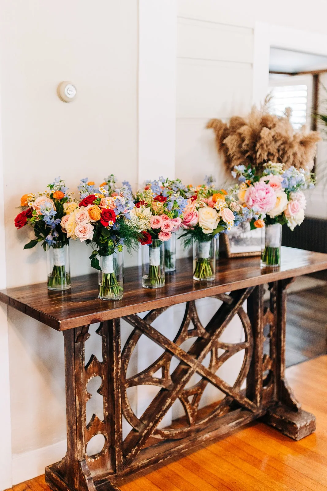 Bouquets of colorful flowers in vases on a rustic wooden table.