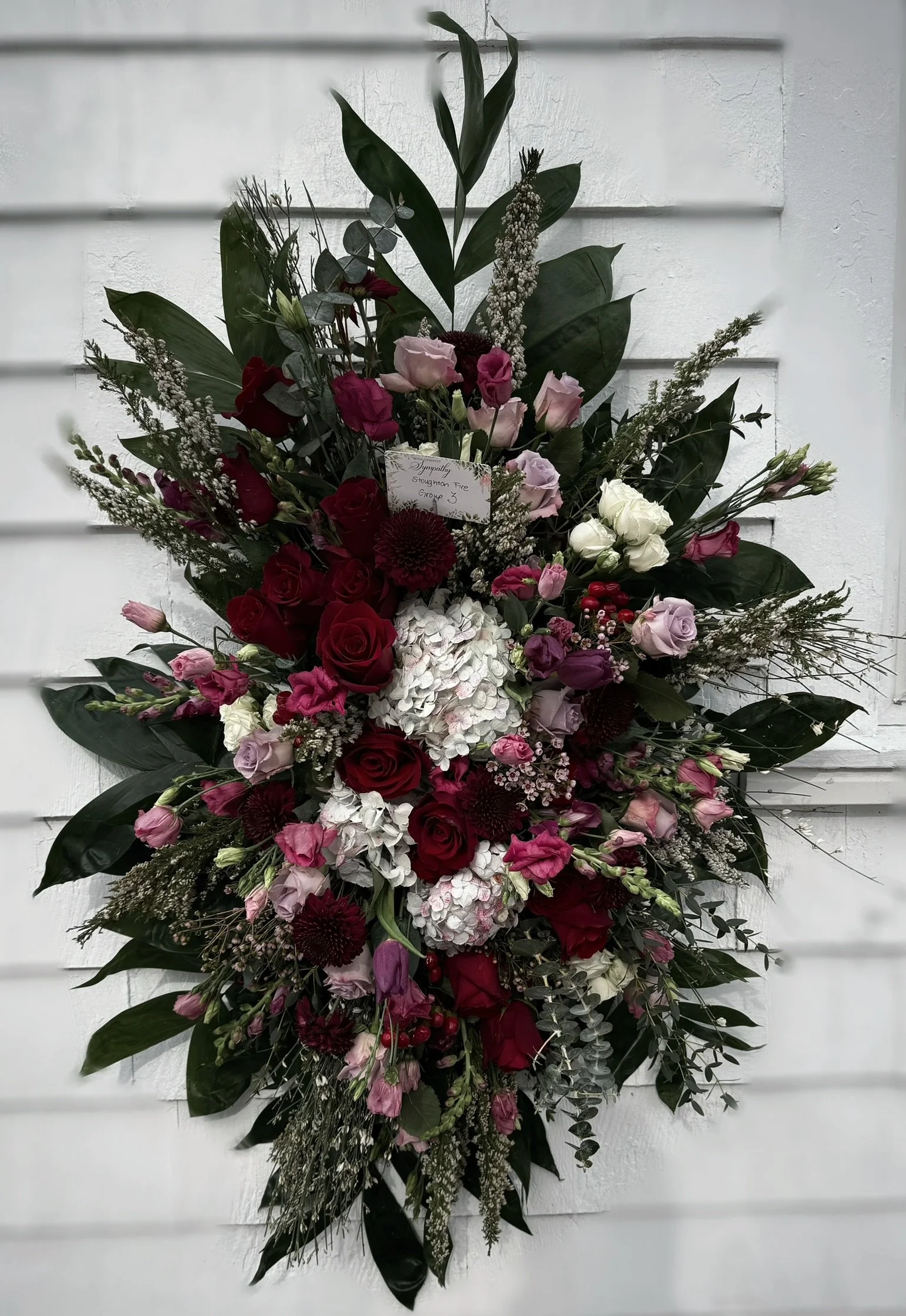 Floral arrangement with roses, hydrangeas, and greenery on white background.