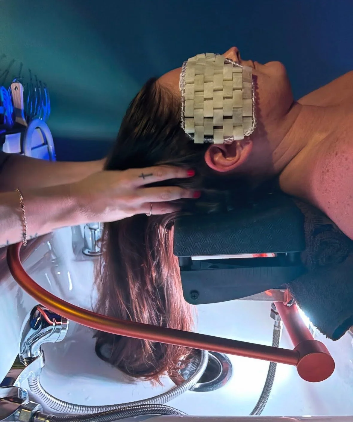A person receiving a massage with their head tilted back, wearing a woven eye mask, in a clinical or spa setting.